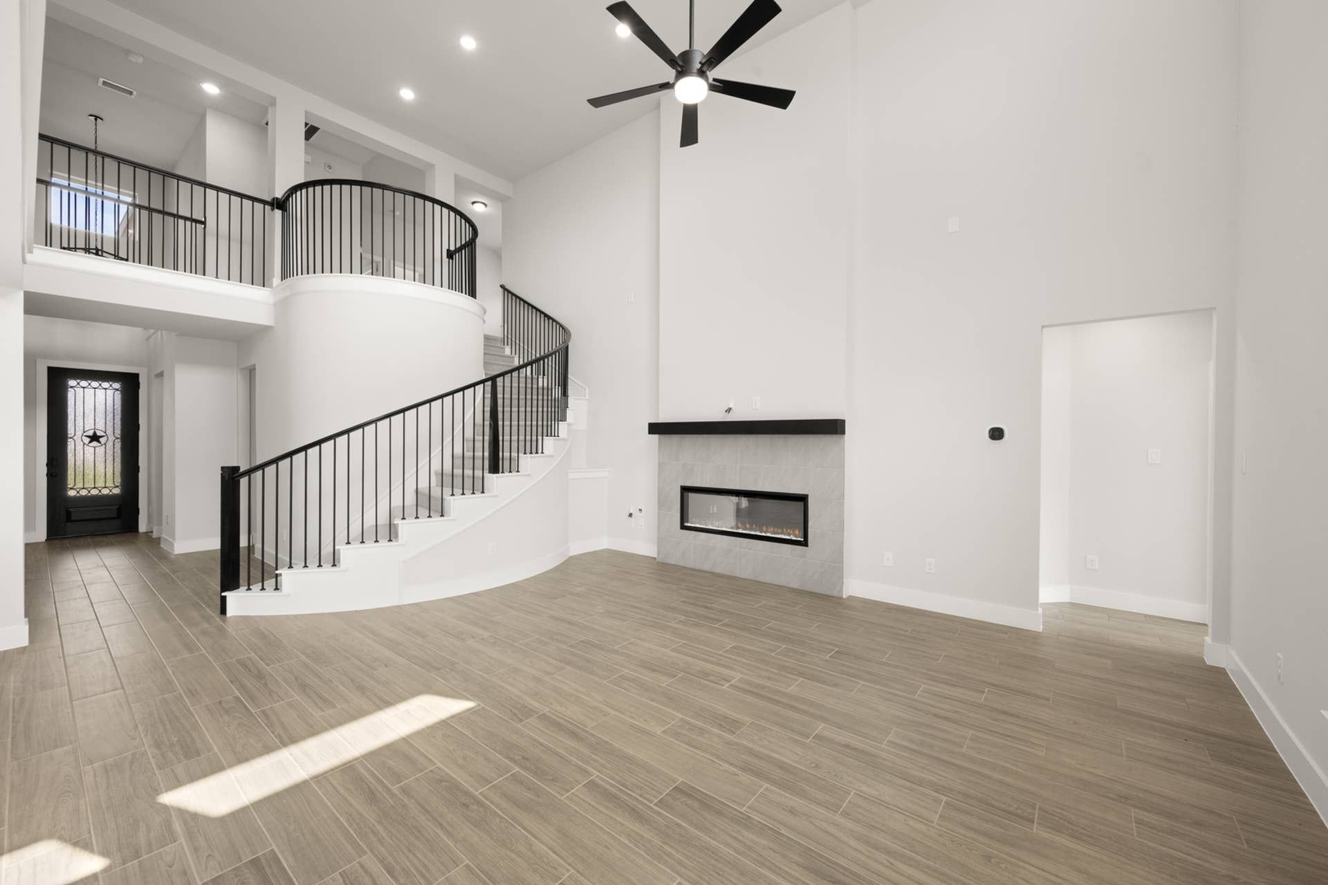 Spacious living room with modern fireplace and elegant spiral staircase.