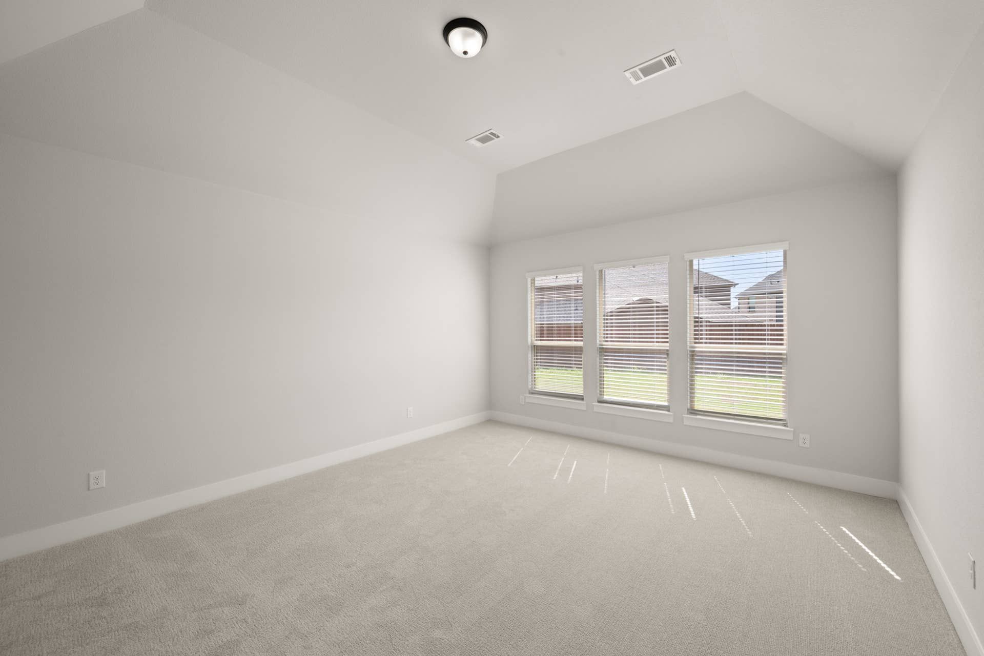 Bright primary suite with large windows and neutral carpet flooring.