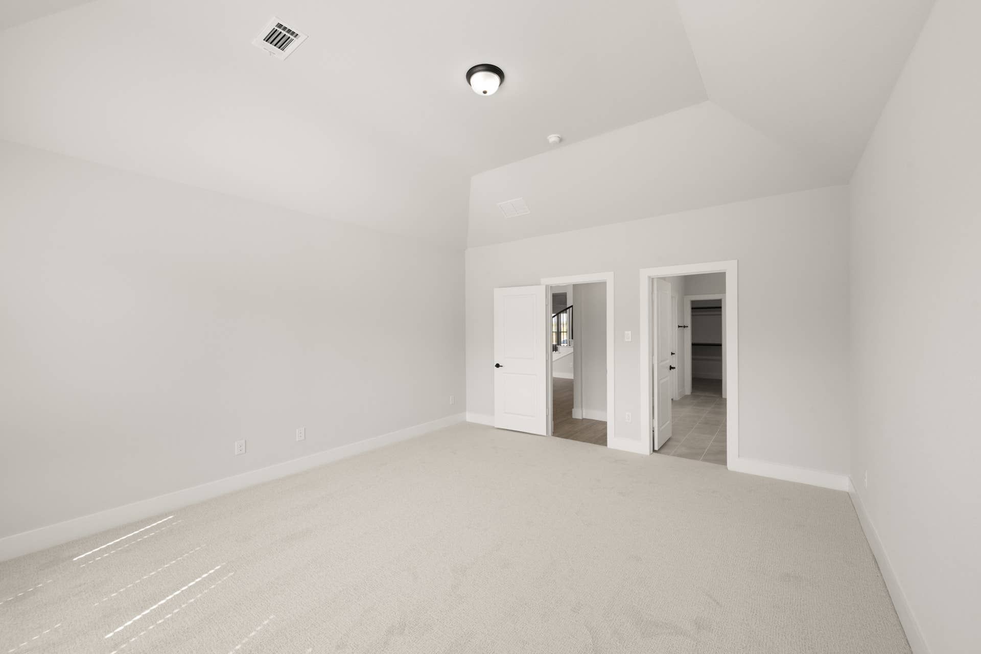 Spacious primary suite with neutral carpet and dual door access.