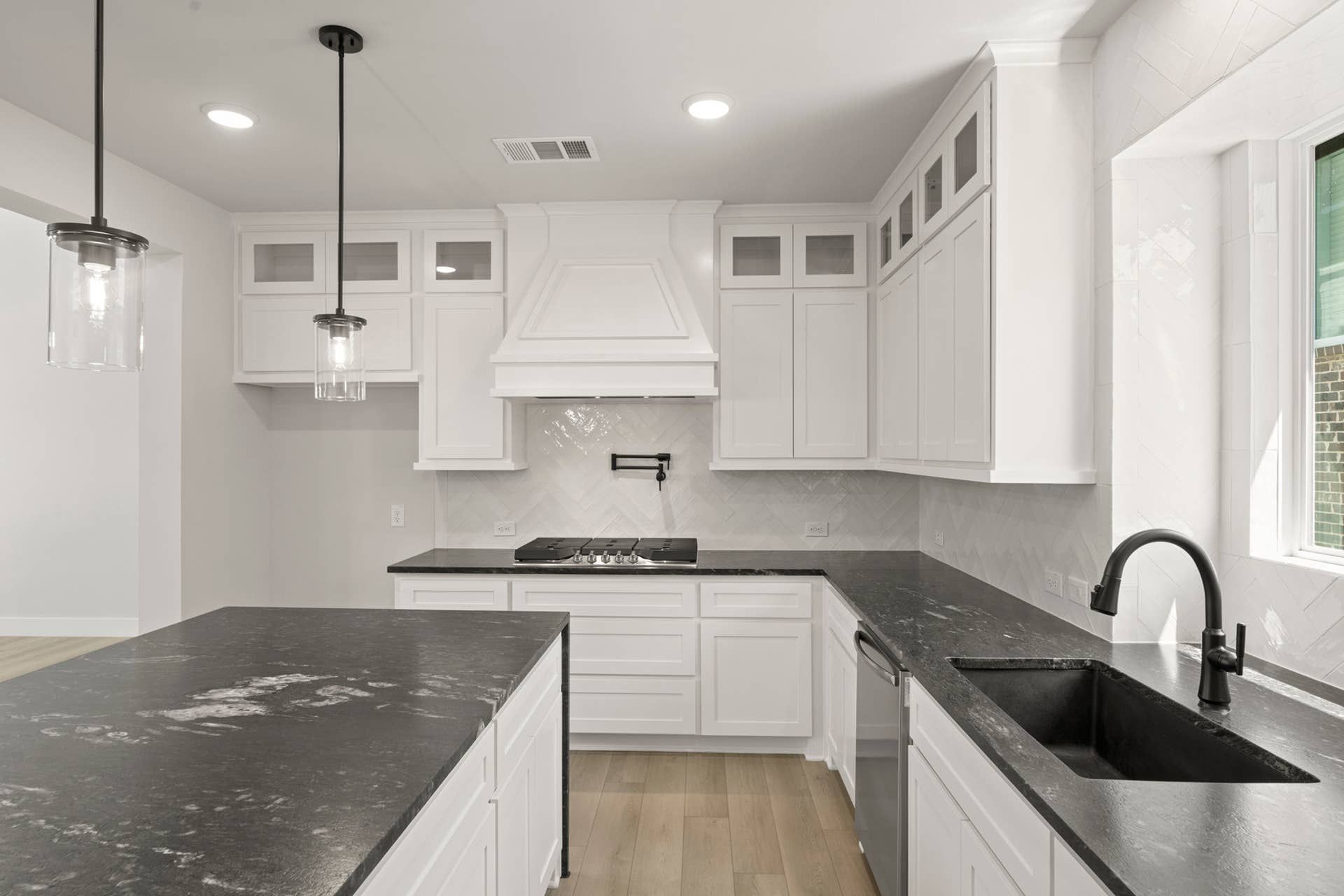 Modern kitchen with white cabinets, black countertops, and pendant lighting.