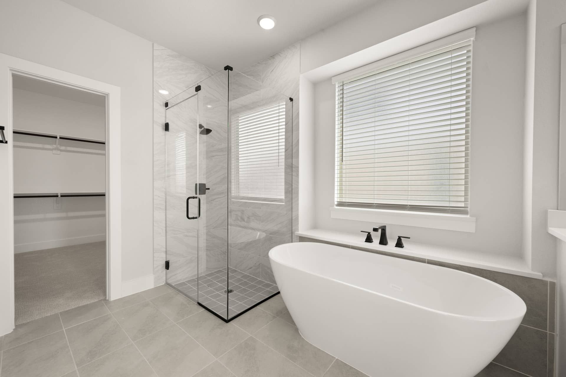 Luxurious bathroom with freestanding tub, glass shower, and walk-in closet.