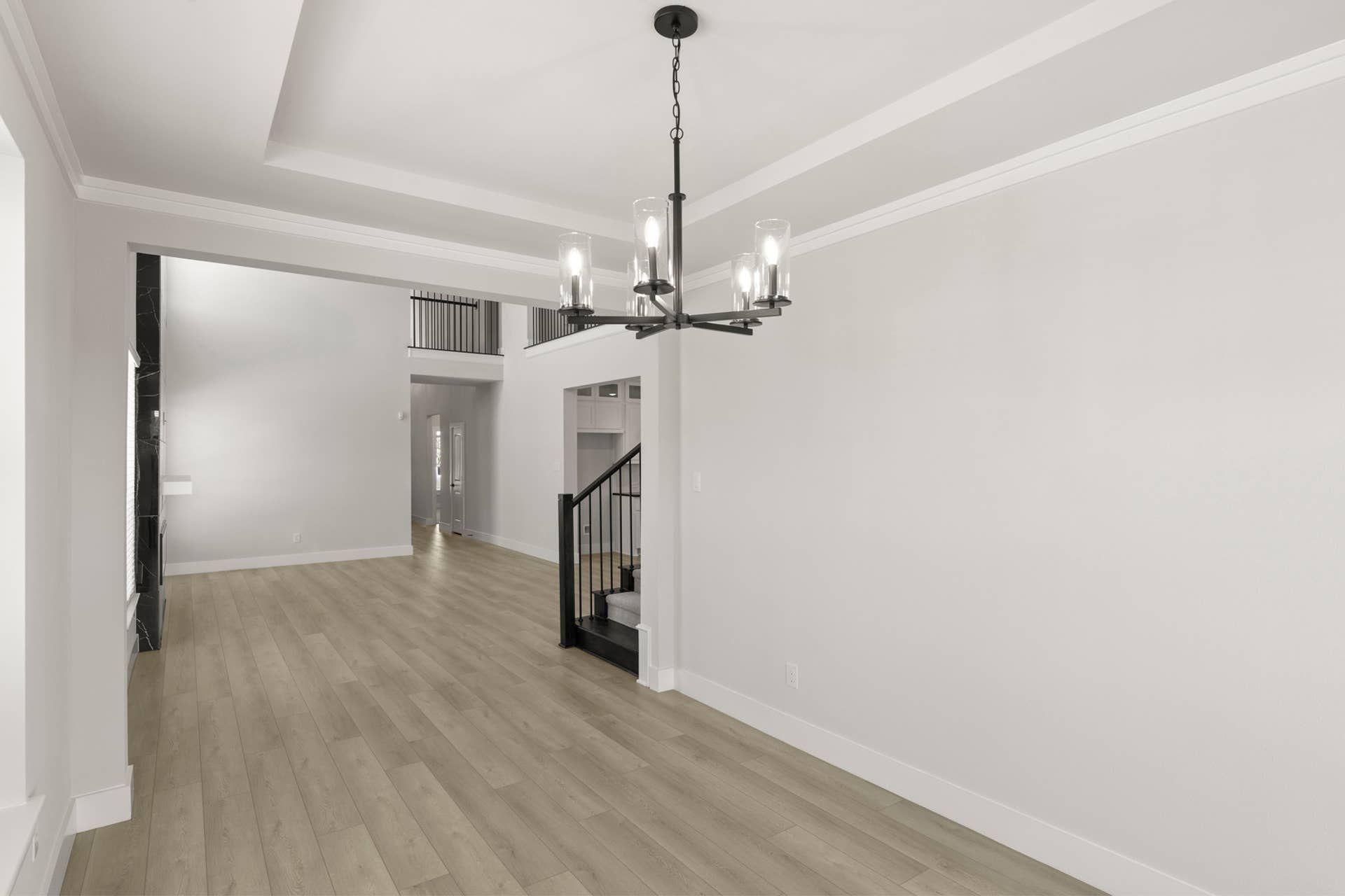 Modern dining room with elegant chandelier and hardwood floors.
