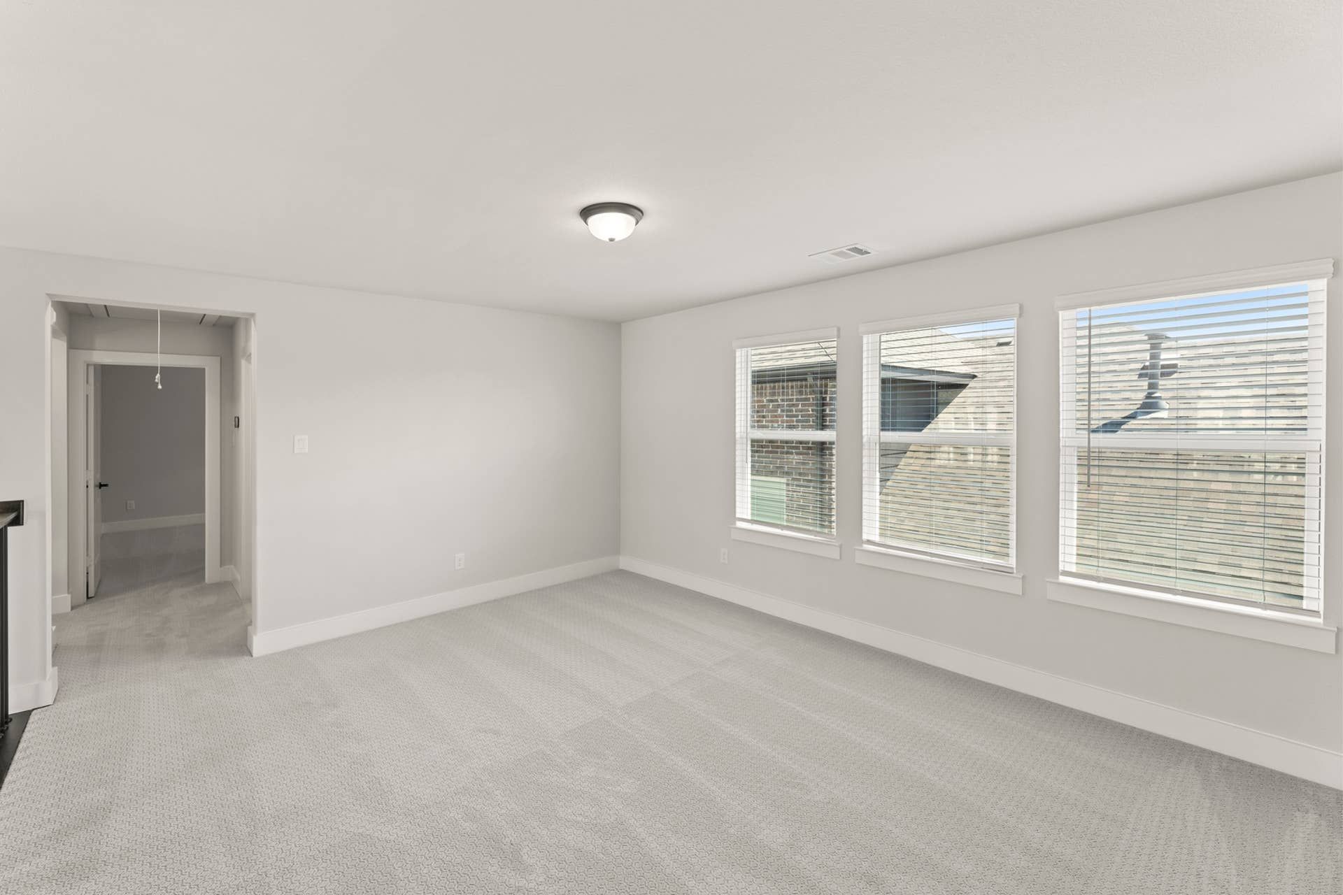Bright, spacious room with large windows and light gray carpet.
