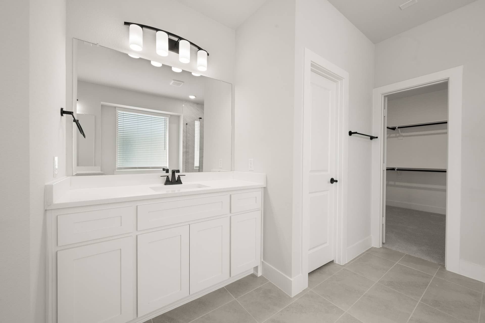 Spacious modern bathroom with white vanity and walk-in closet.