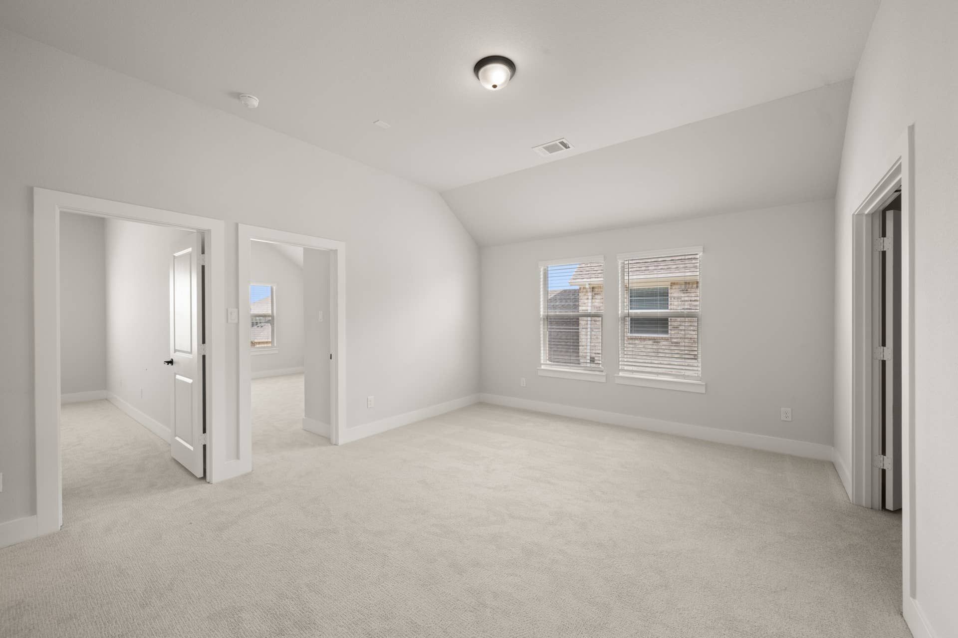 Spacious carpeted game room with natural light and multiple doorways.