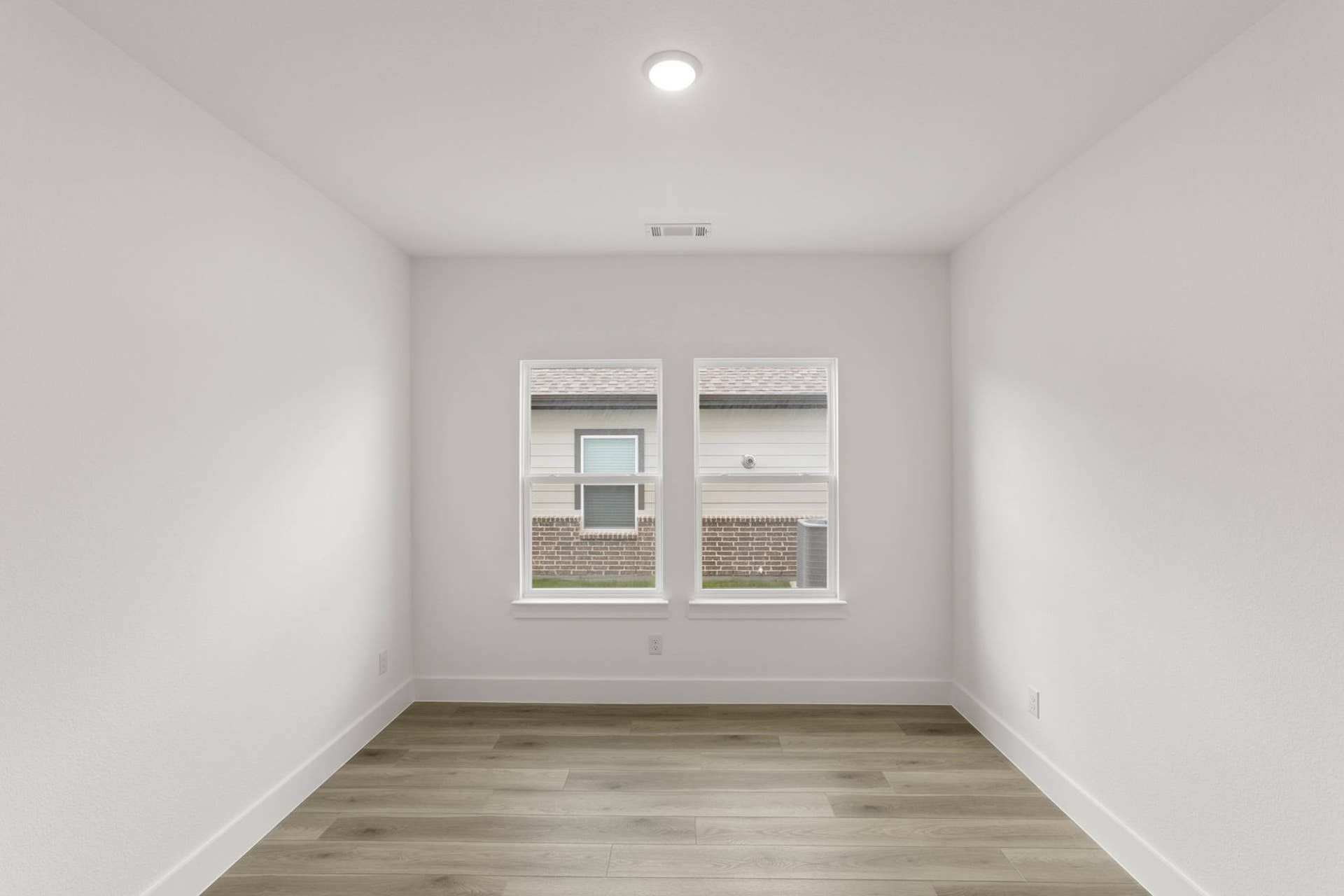 Bright study room with wood flooring and double windows.