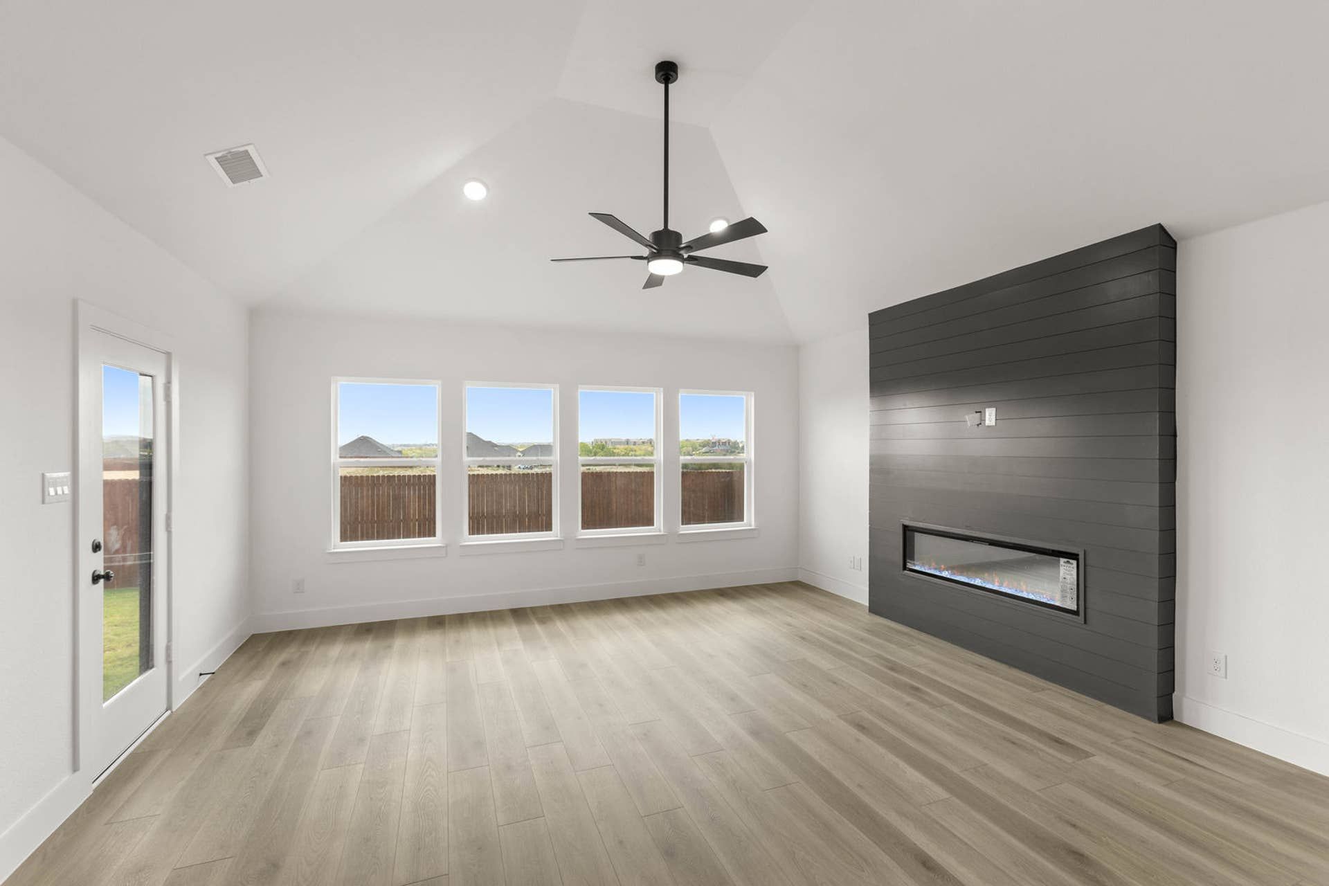 Spacious living room with vaulted ceiling, modern fireplace, and large windows.