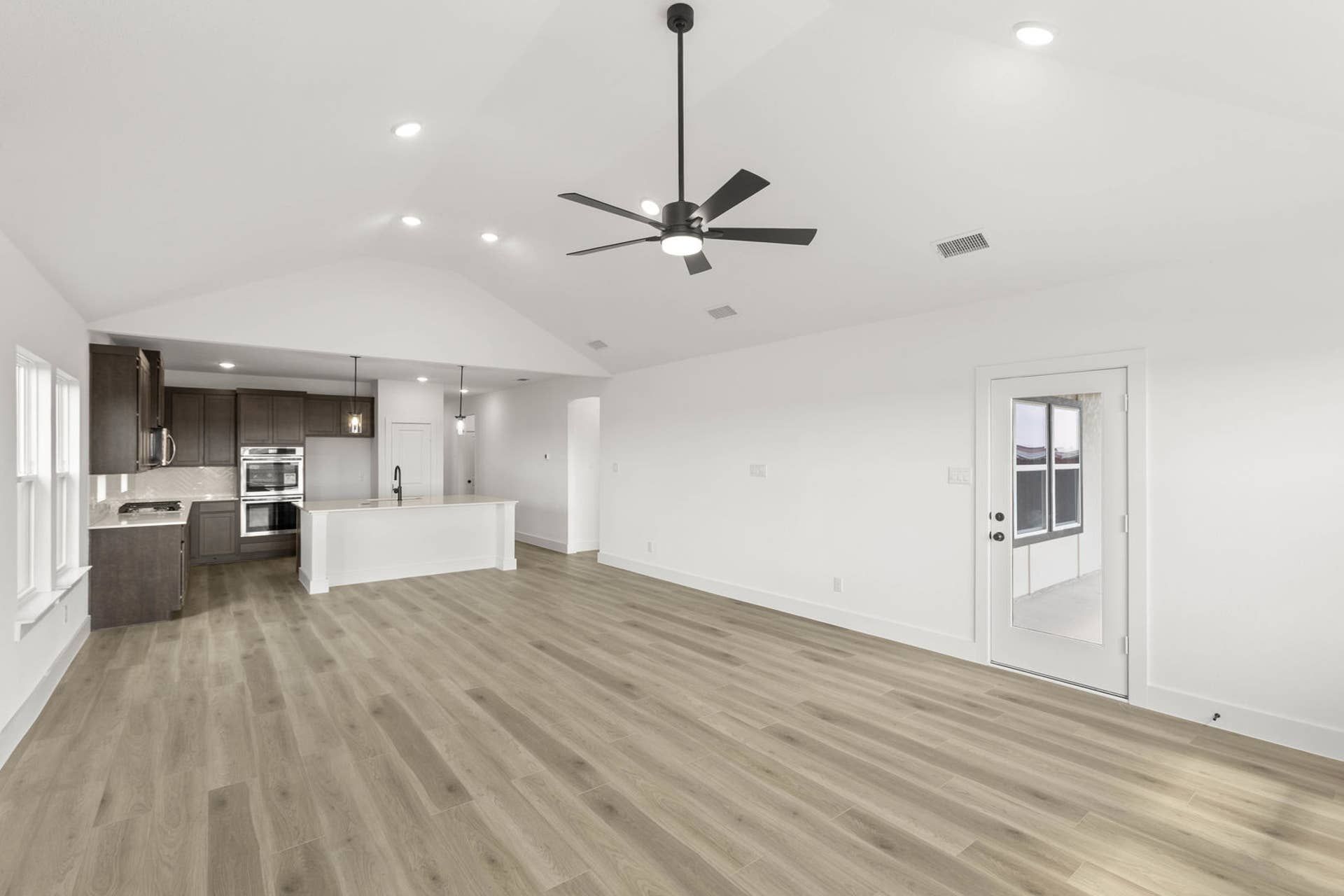 Spacious modern living room with vaulted ceiling and open kitchen design.