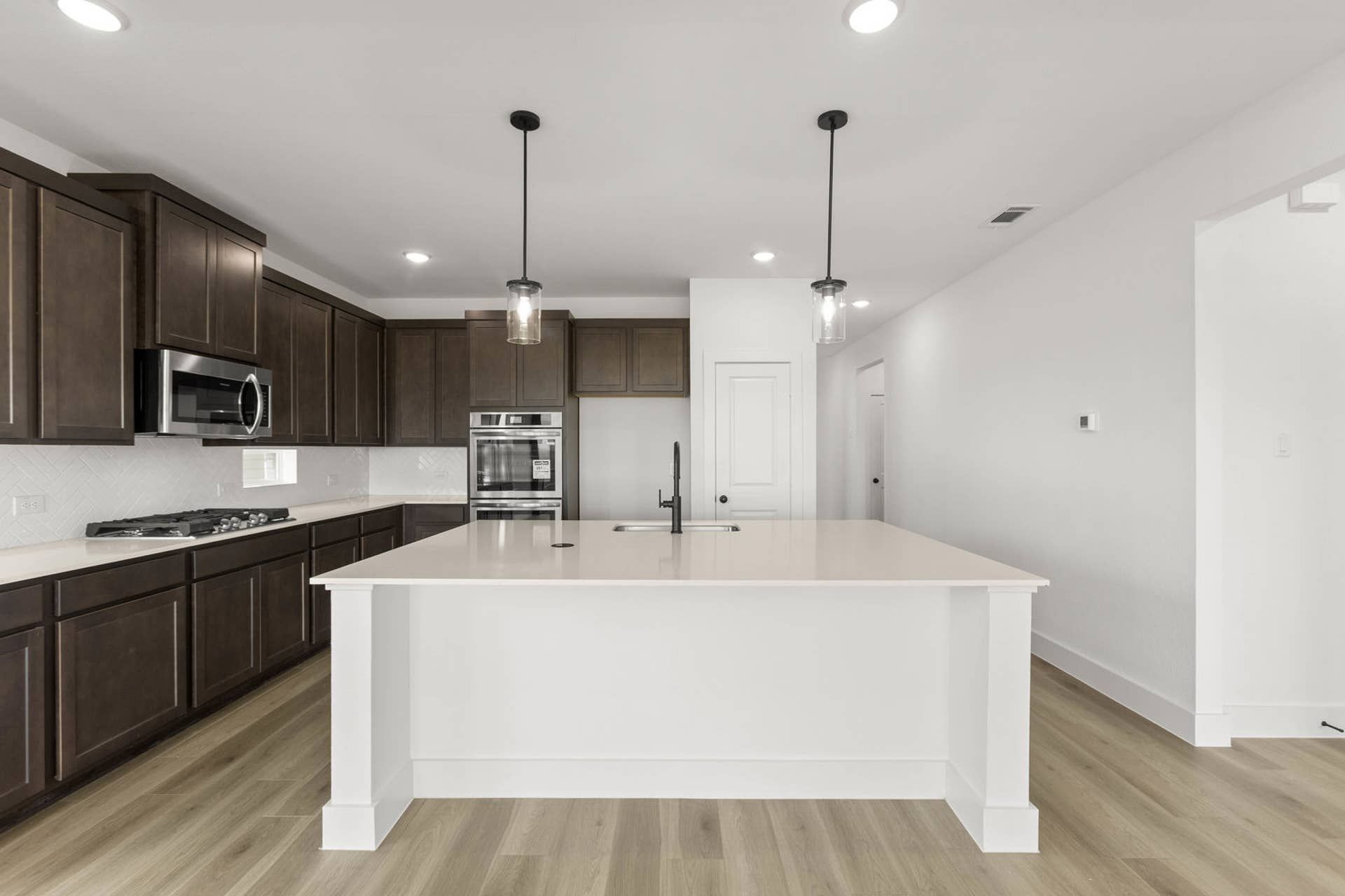 Modern kitchen with dark wood cabinets and white island countertop.