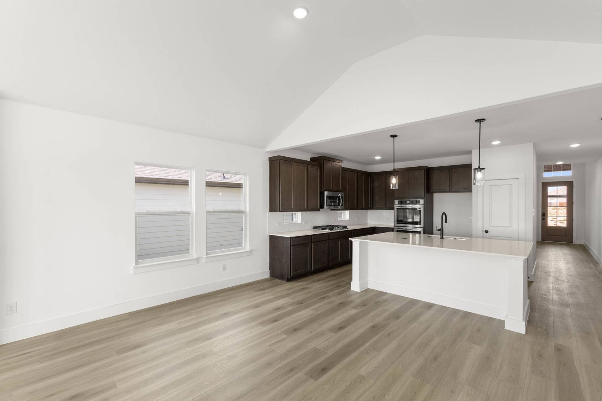 Modern kitchen with dark cabinets, light flooring, and large island.