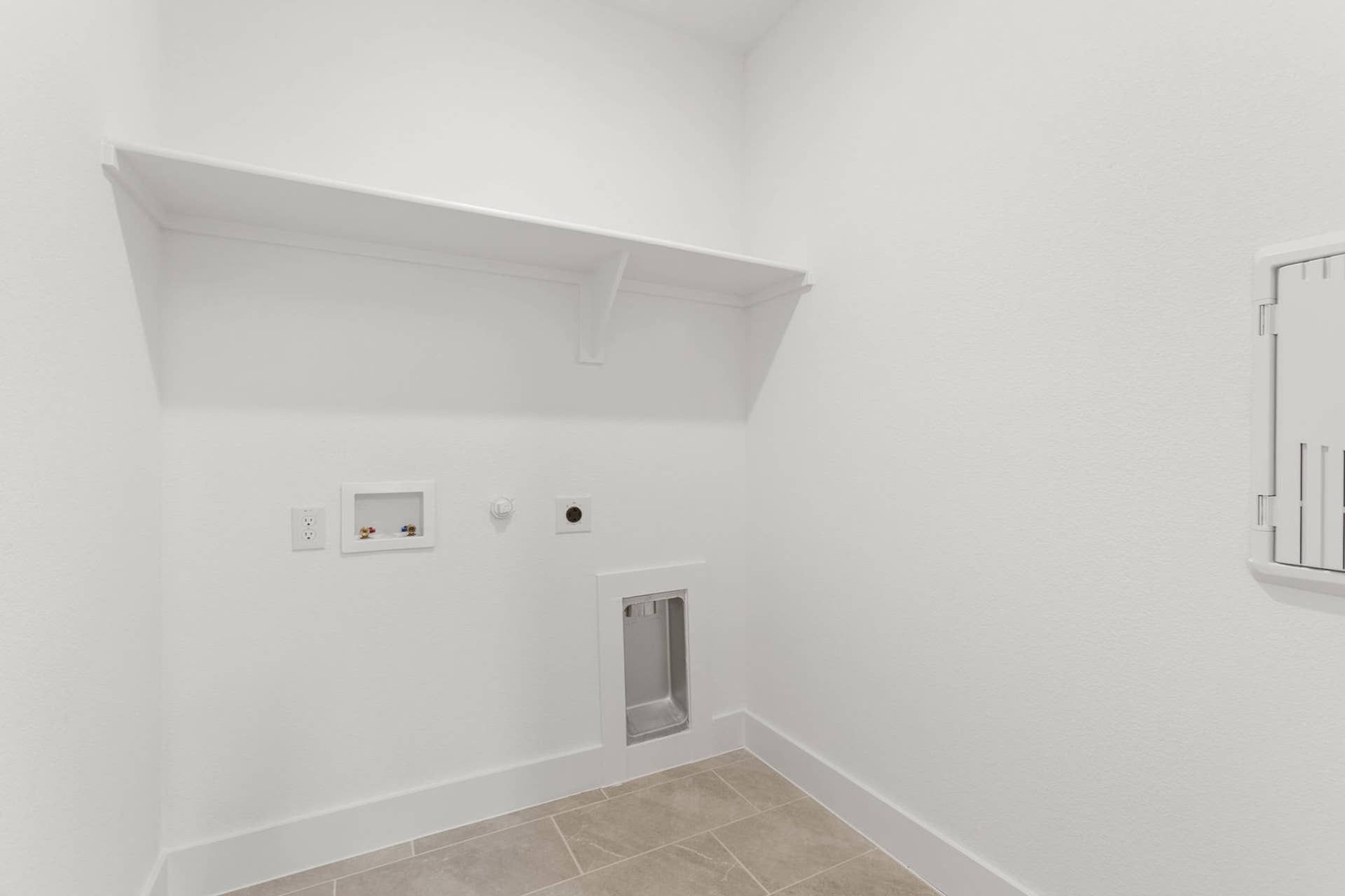 Utility room with wall shelf and water hookups.