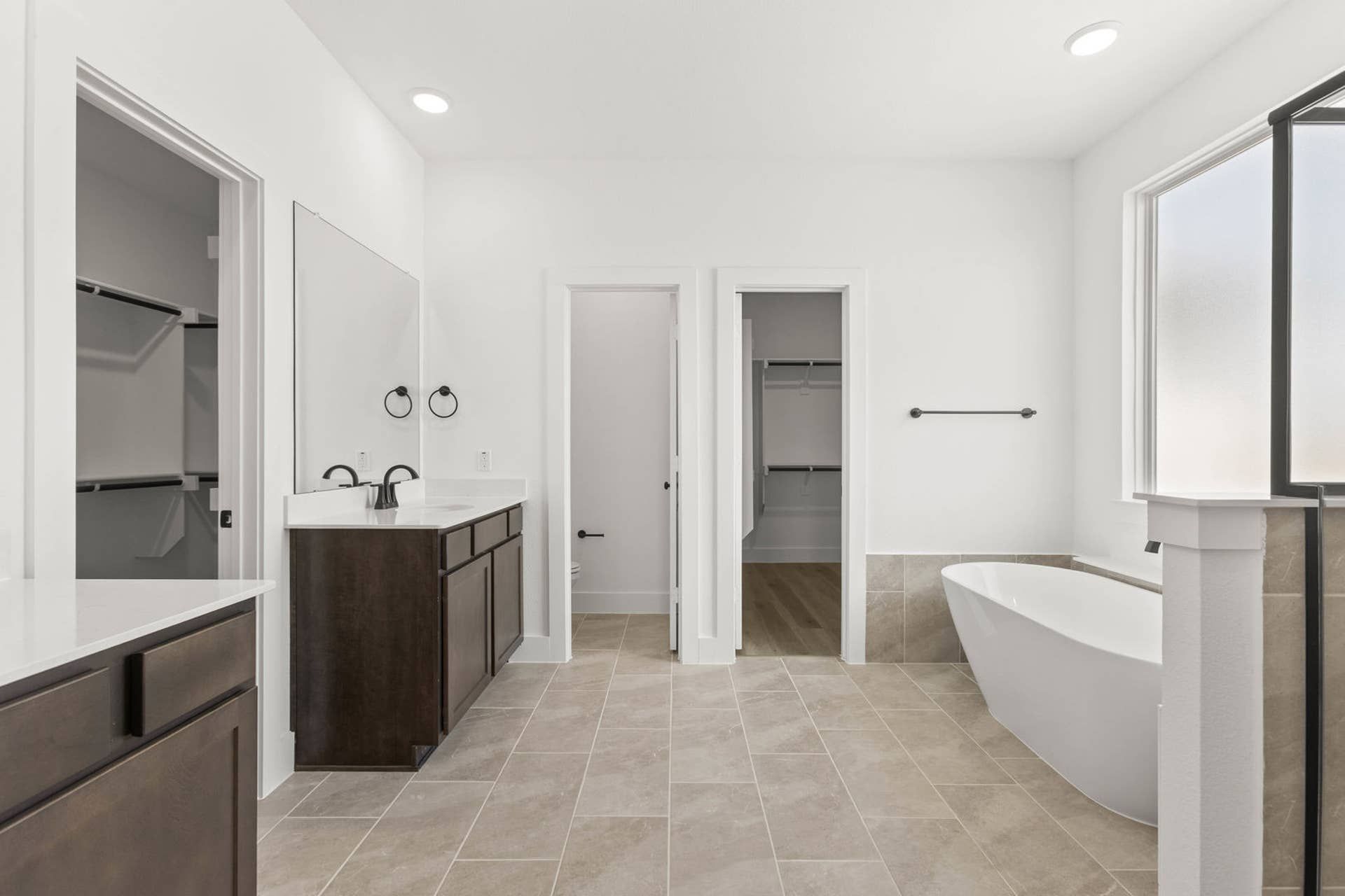 Spacious primary suite bathroom with freestanding tub, dual vanities, and walk-in closets.