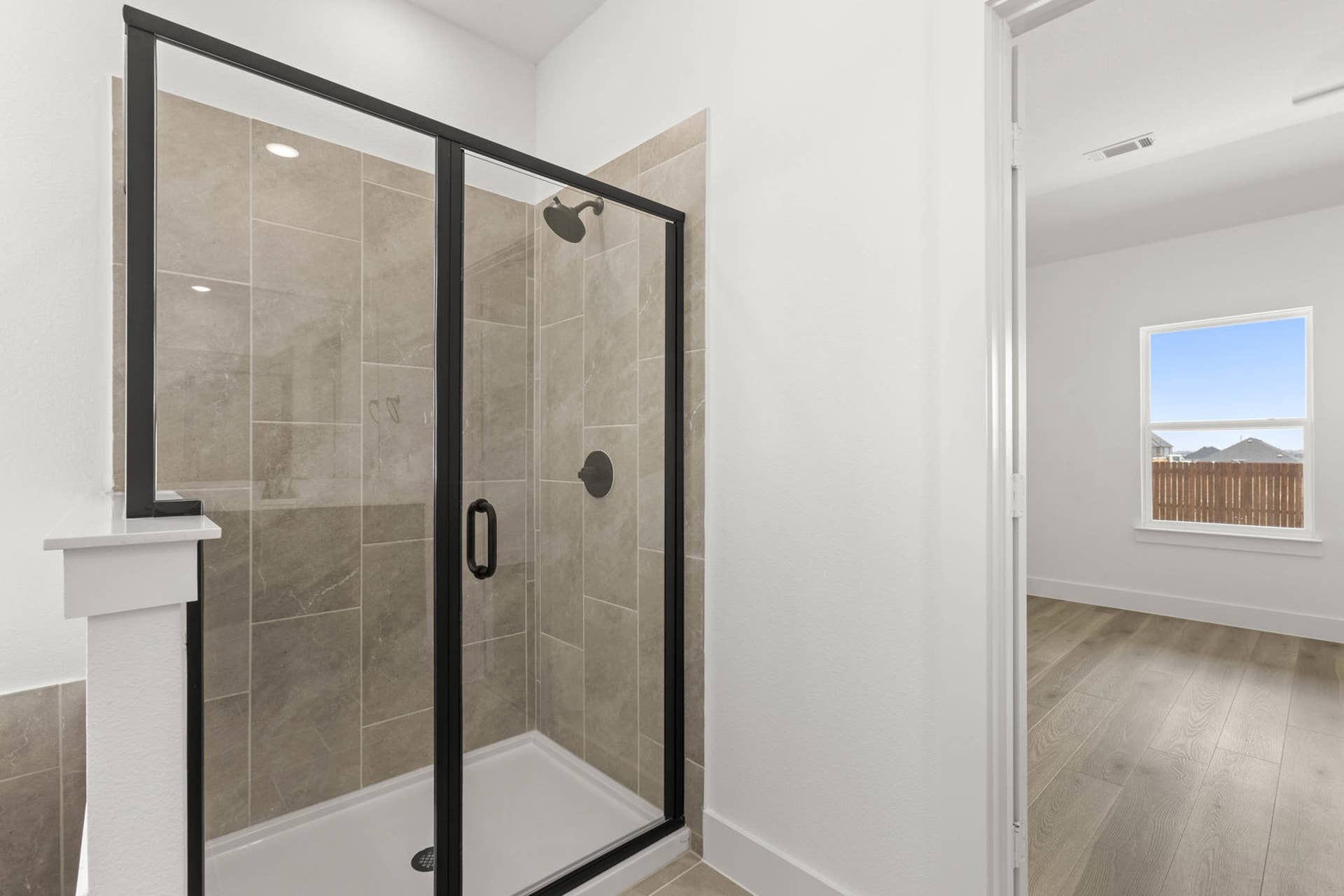 Modern bathroom with glass shower enclosure and tiled walls.