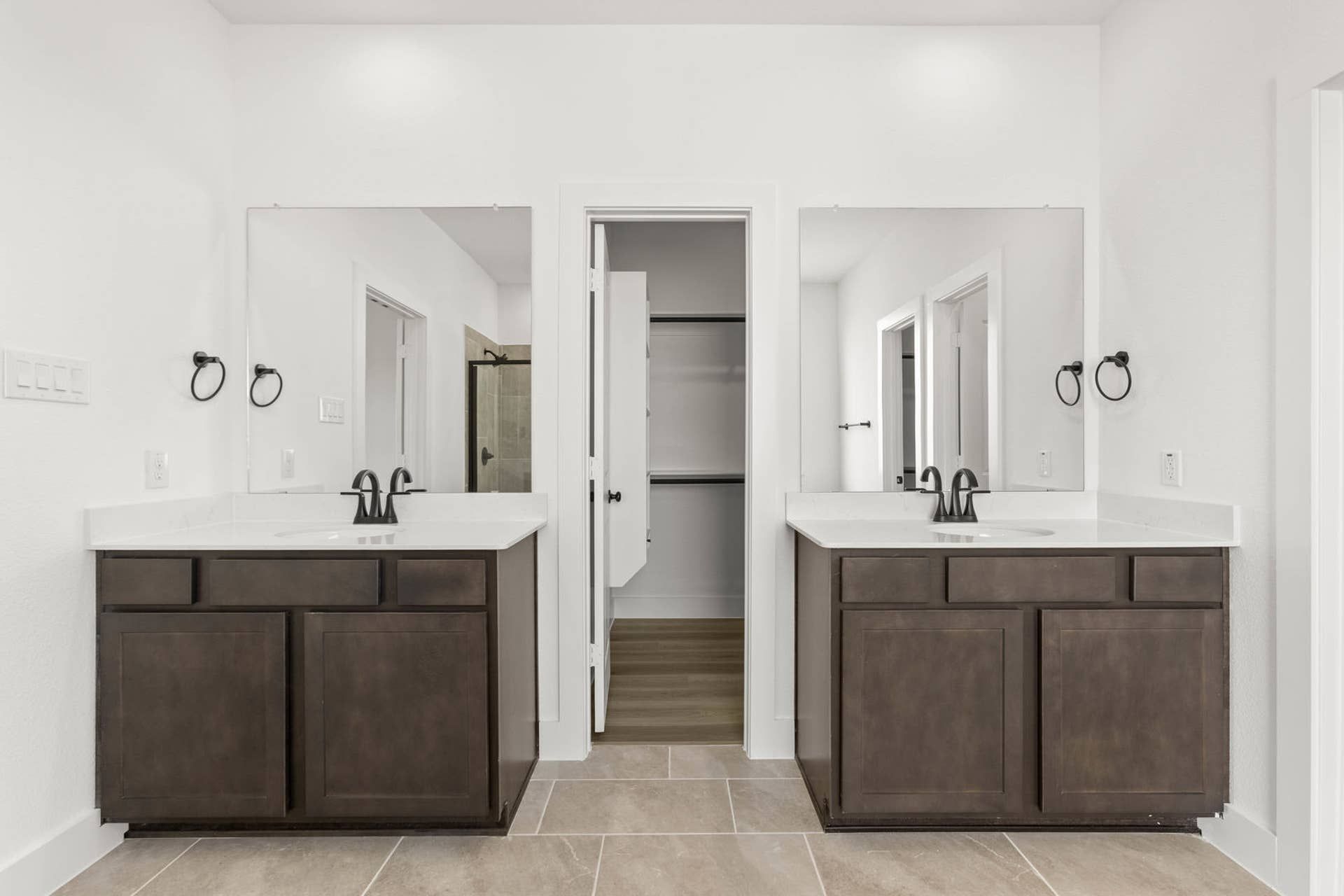 Modern bathroom with dual vanities, large mirrors, and walk-in closet.