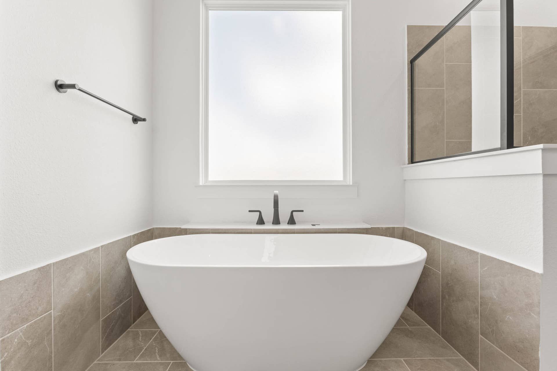 Luxurious bathroom with a freestanding tub and frosted window.