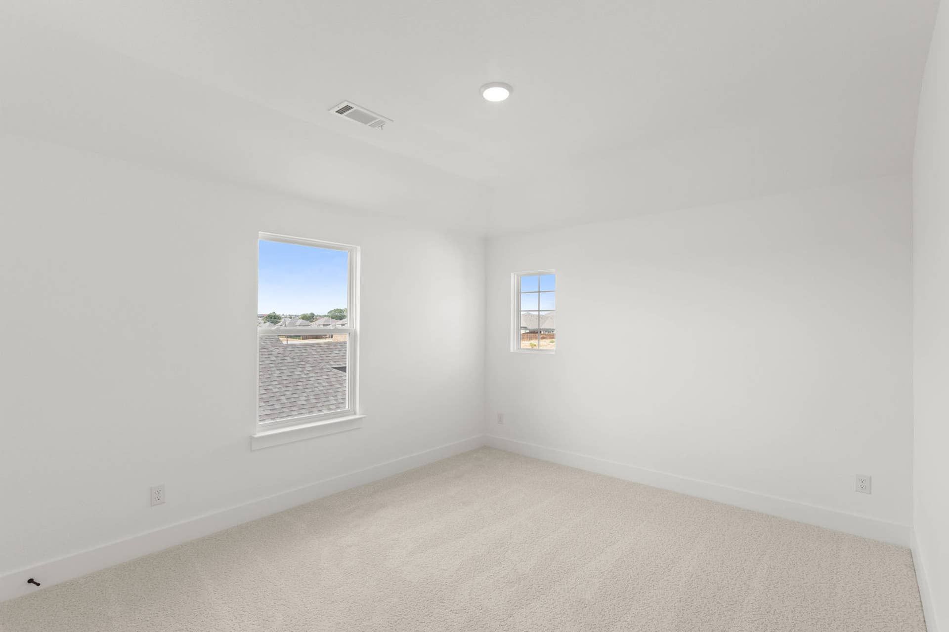 Bright, empty bedroom with white walls and large windows.