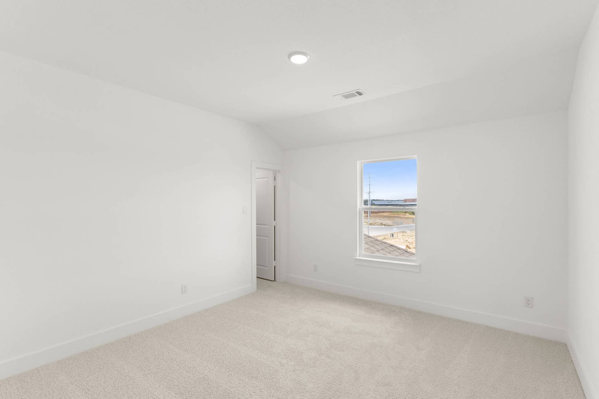 Bright, carpeted bedroom with white walls and a window view.
