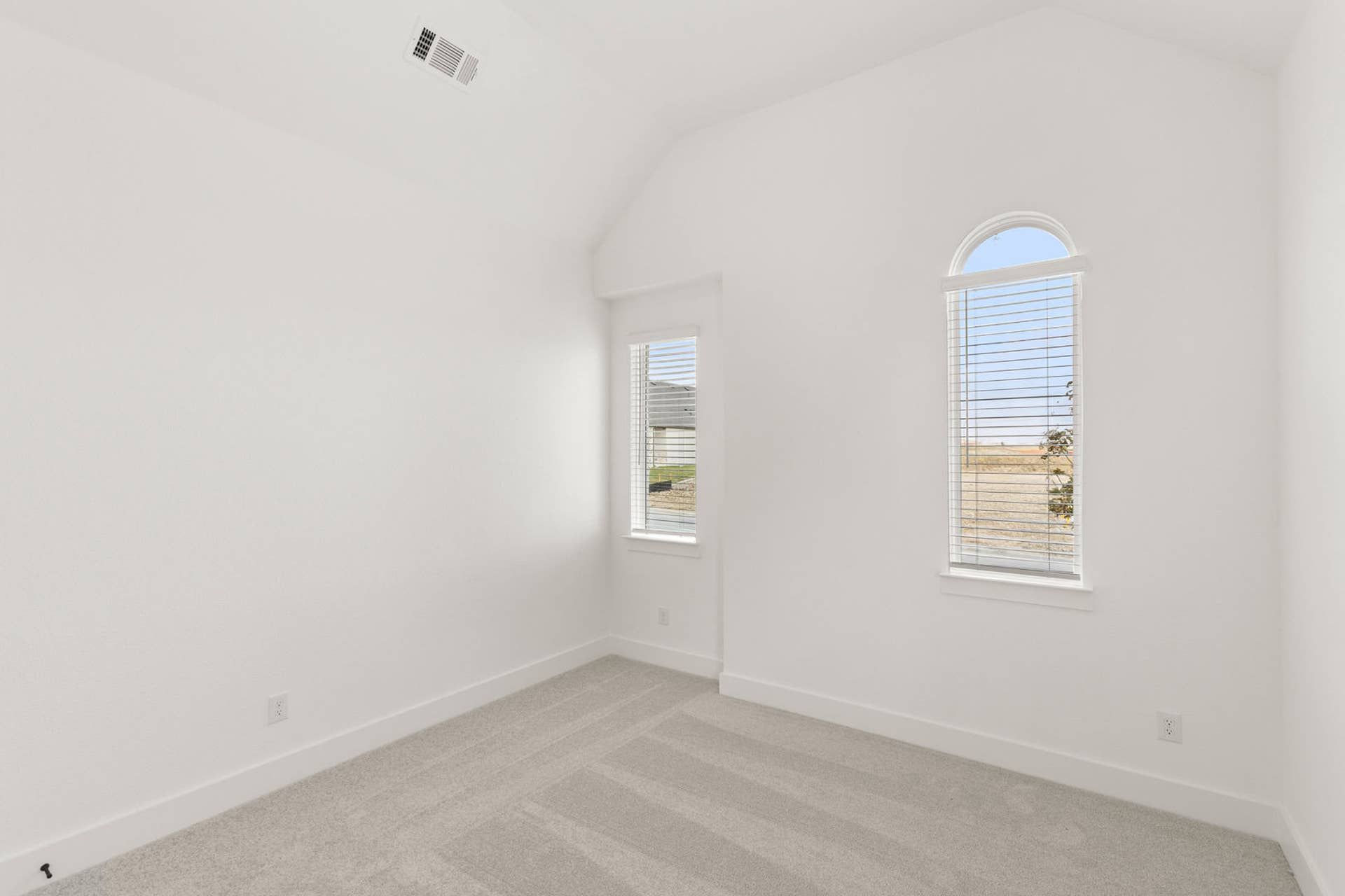 Bright bedroom with vaulted ceiling and arched window.