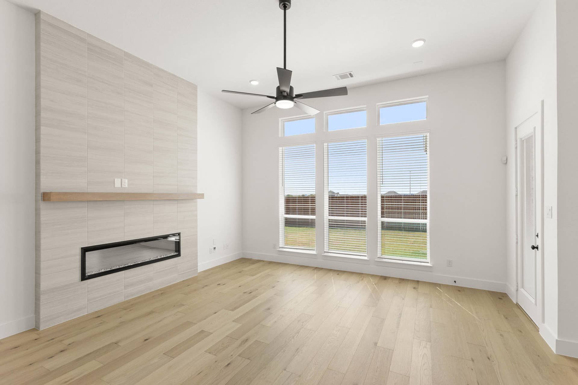 Spacious living room with large windows, ceiling fan, and modern fireplace.