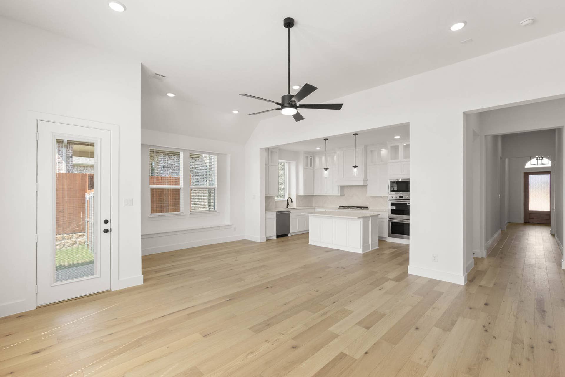 Spacious living room with light wood floors and modern kitchen island.