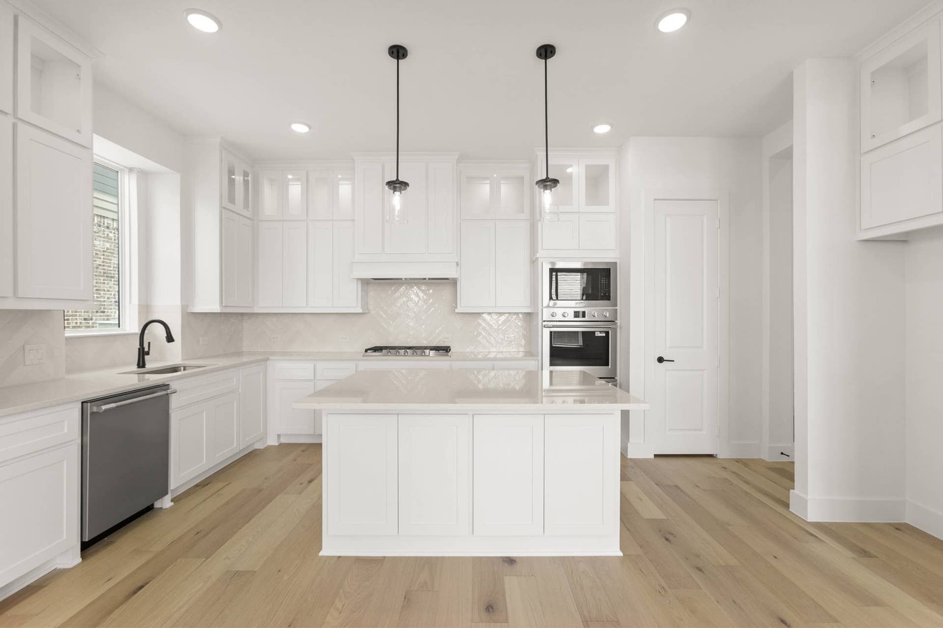 Modern kitchen with white cabinetry, island, and stainless steel appliances.
