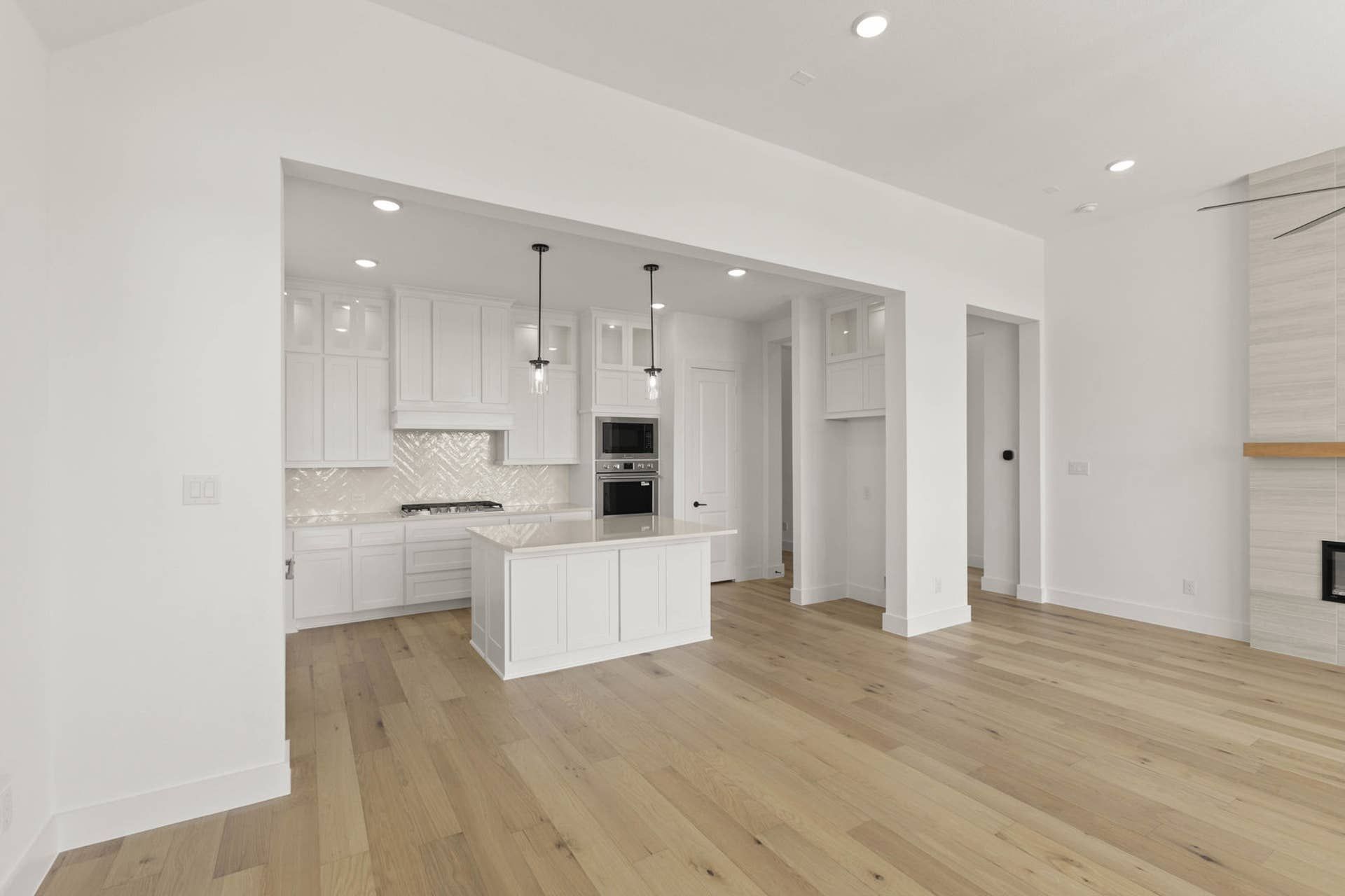 Modern kitchen with white cabinetry, island, and hardwood floors.