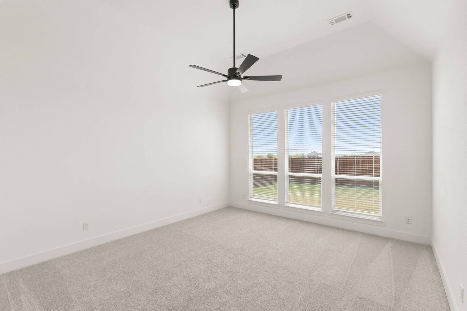 Spacious primary suite with large windows and modern ceiling fan.