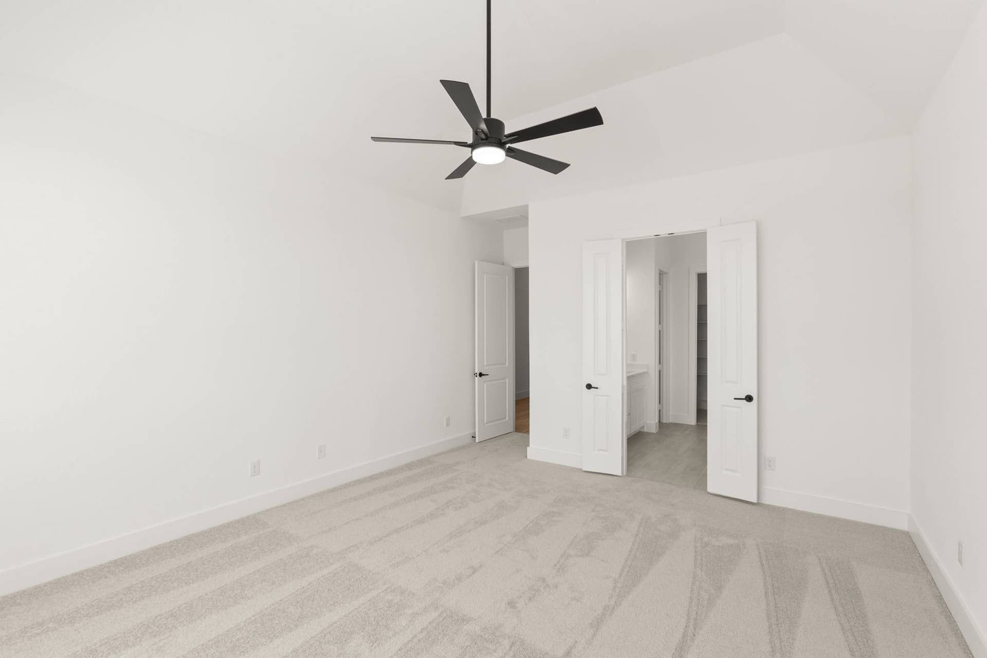 Spacious primary suite with carpeted flooring and ceiling fan.