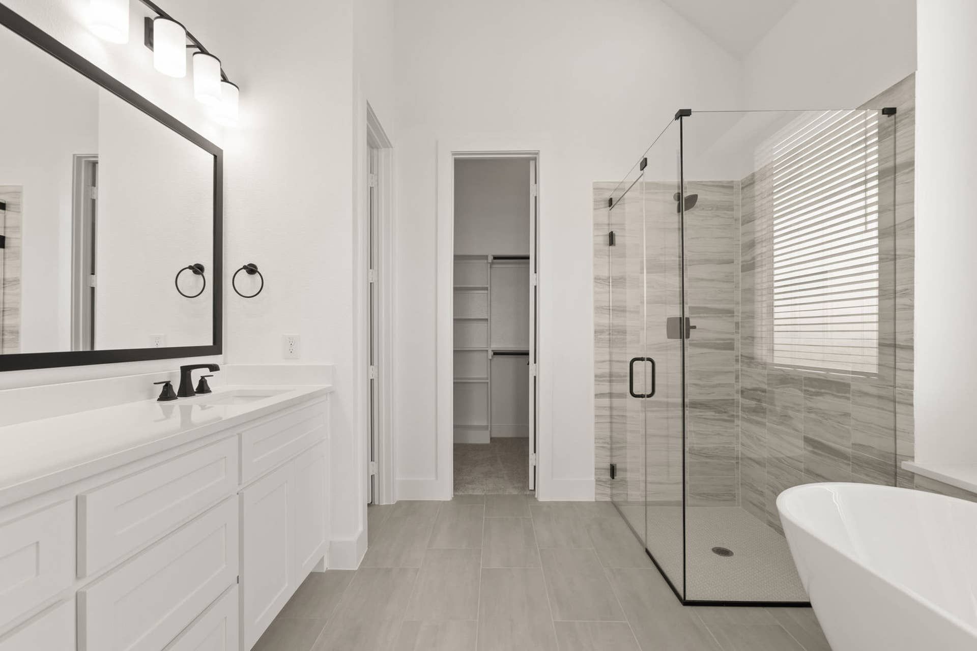 Modern bathroom with glass shower, freestanding tub, and double vanity.