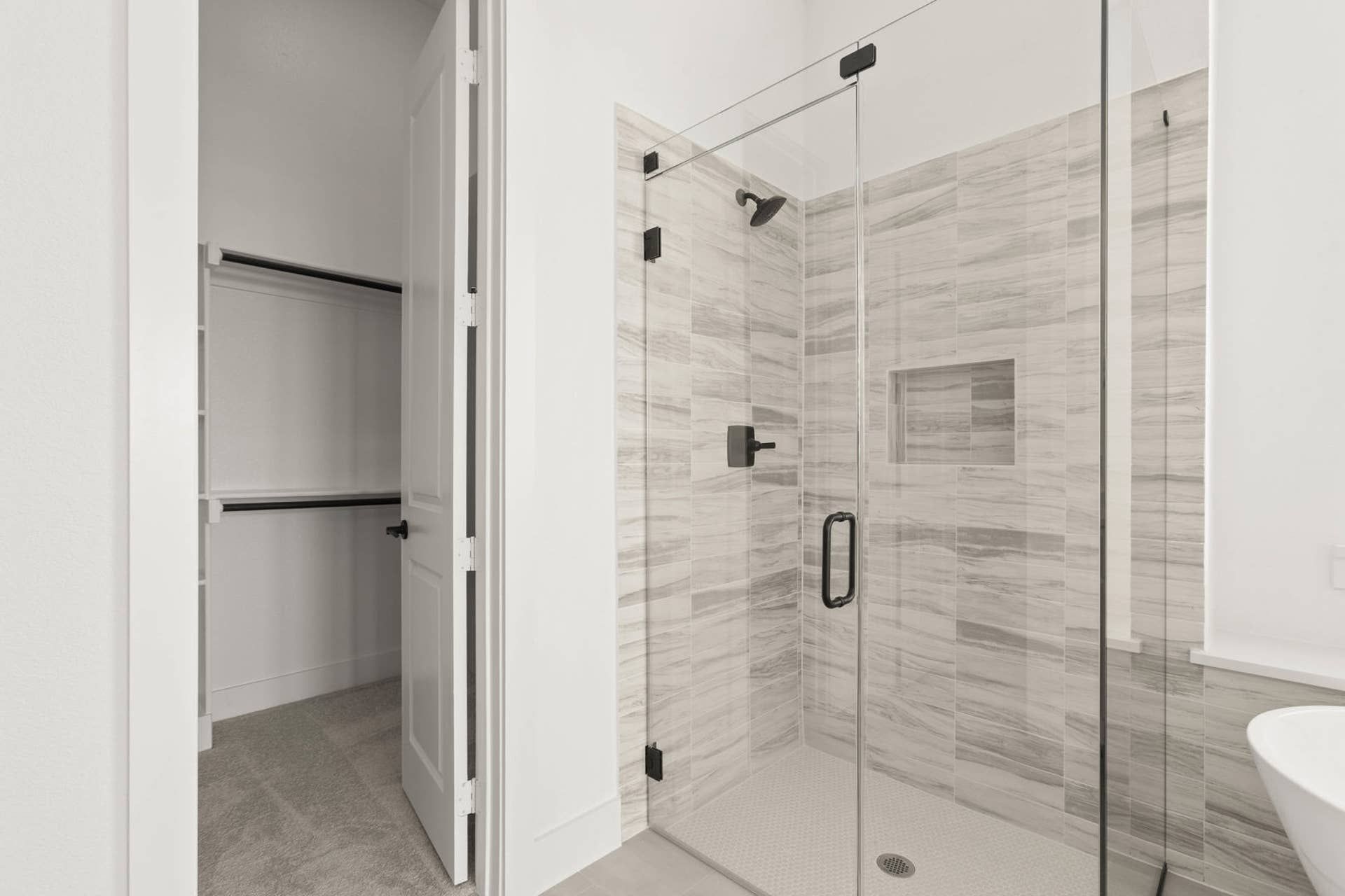 Modern bathroom with glass-enclosed shower and adjacent walk-in closet.