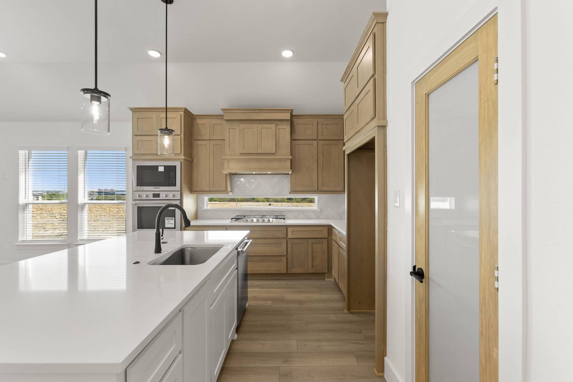 Modern kitchen with island, wooden cabinets, and pendant lighting.