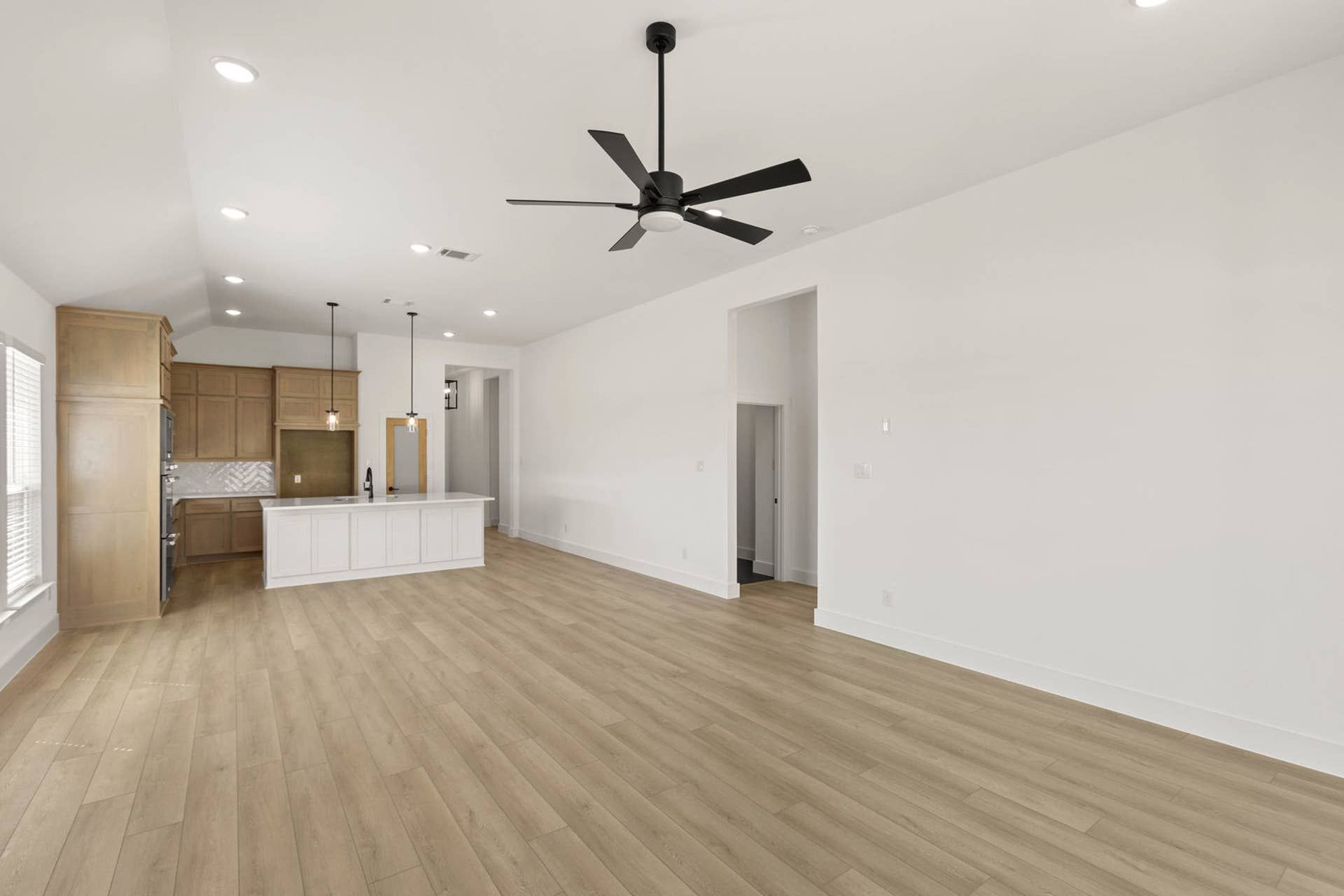 Spacious living room with hardwood floors and modern open kitchen design.