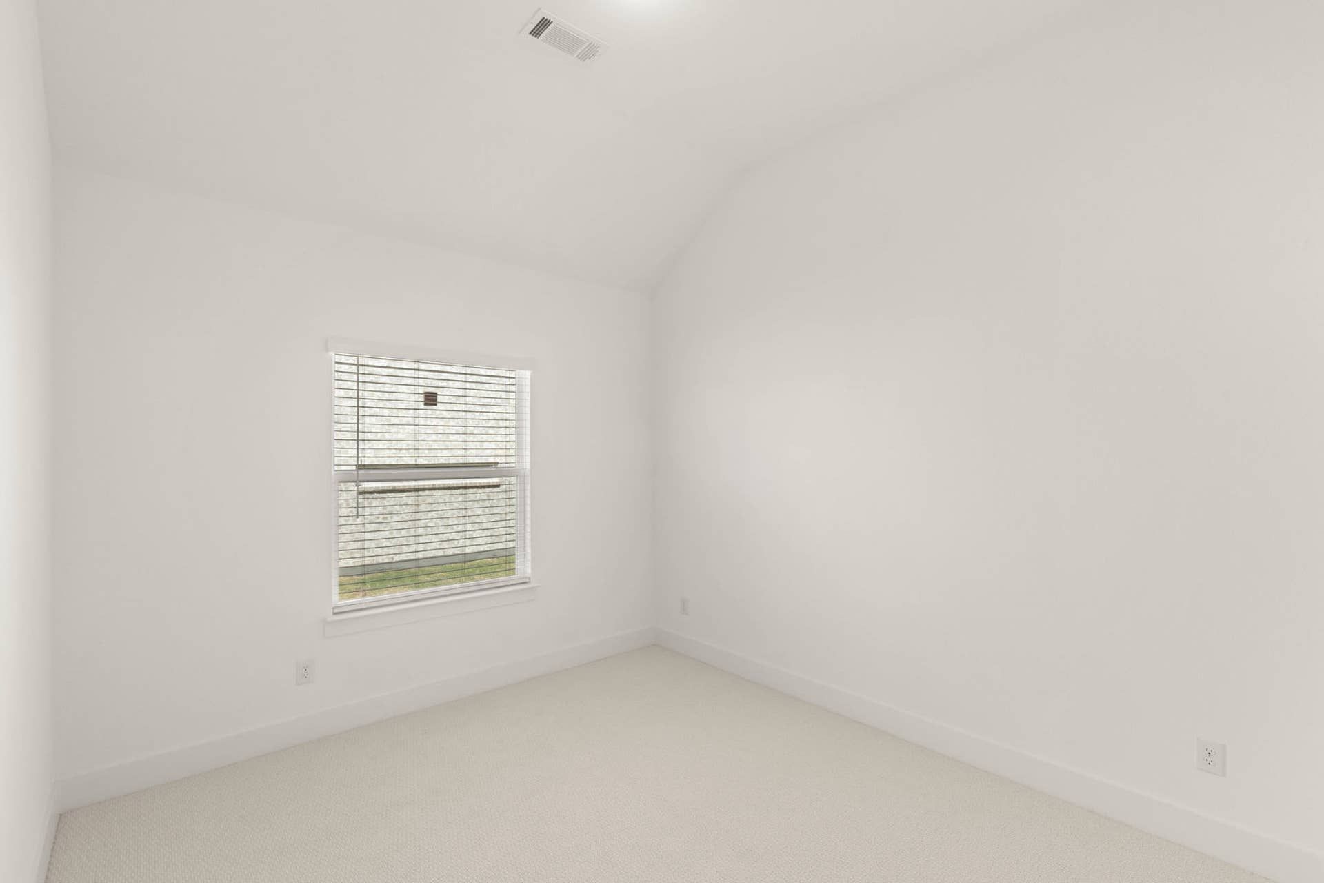 Minimalist white bedroom with window and vaulted ceiling.