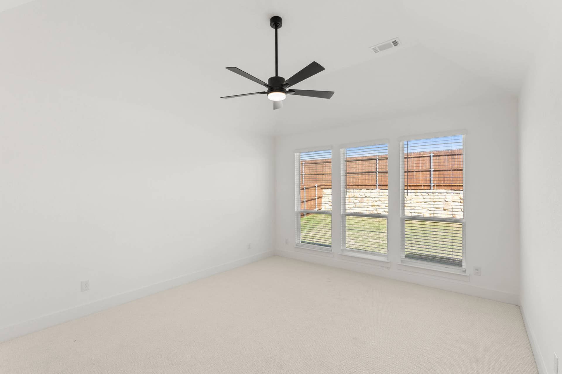 Bright primary suite interior with ceiling fan and large windows.