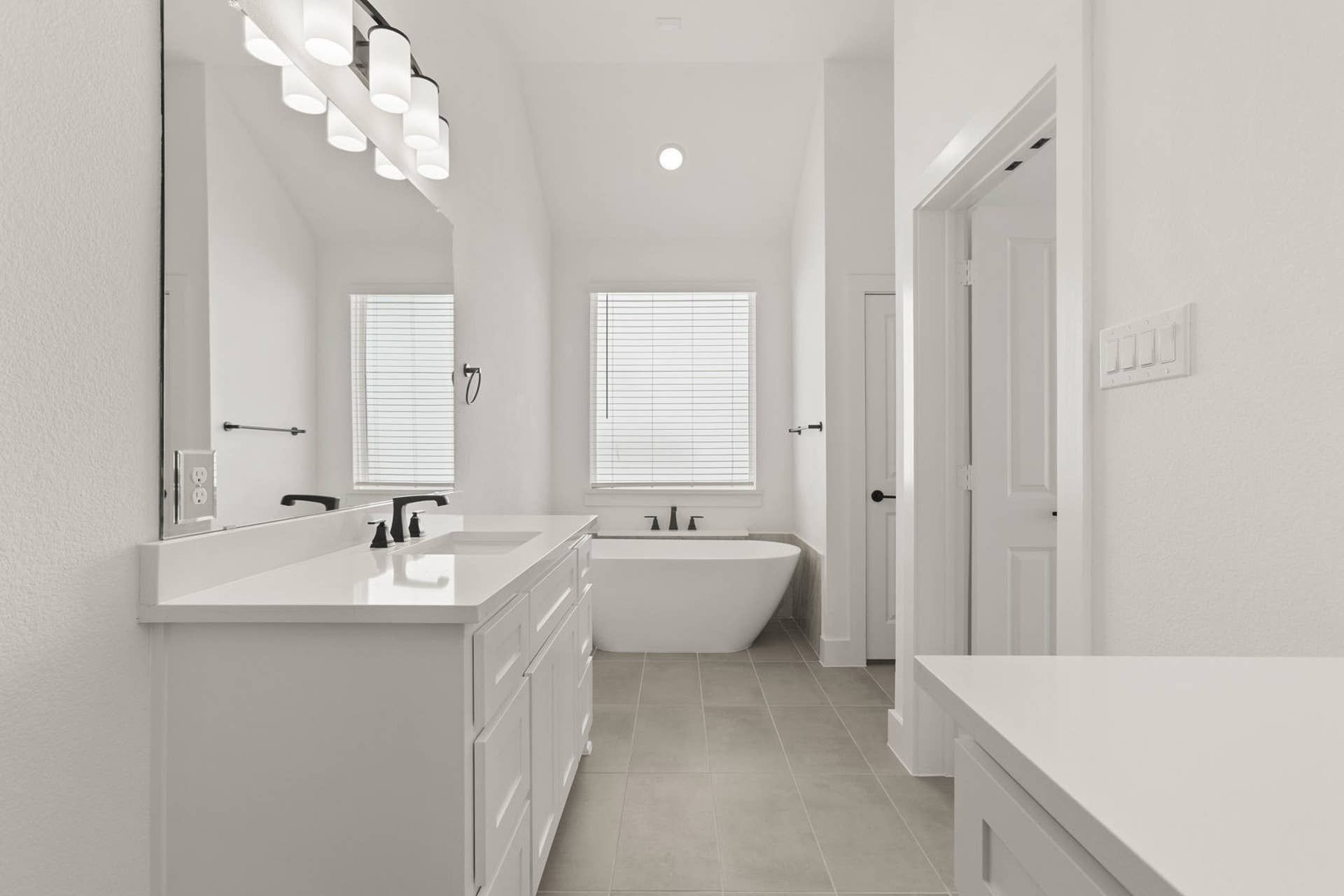 Modern bathroom with double vanity, freestanding tub, and soft natural lighting.