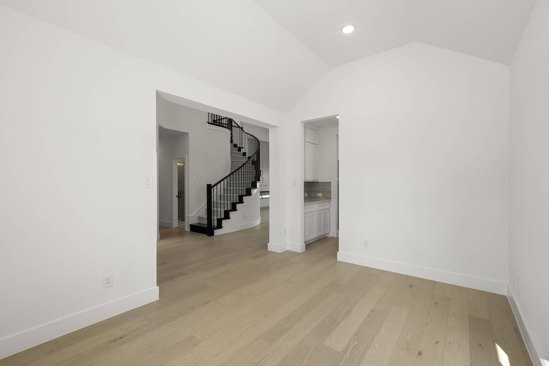 Interior with open space, hardwood floors, and winding staircase.
