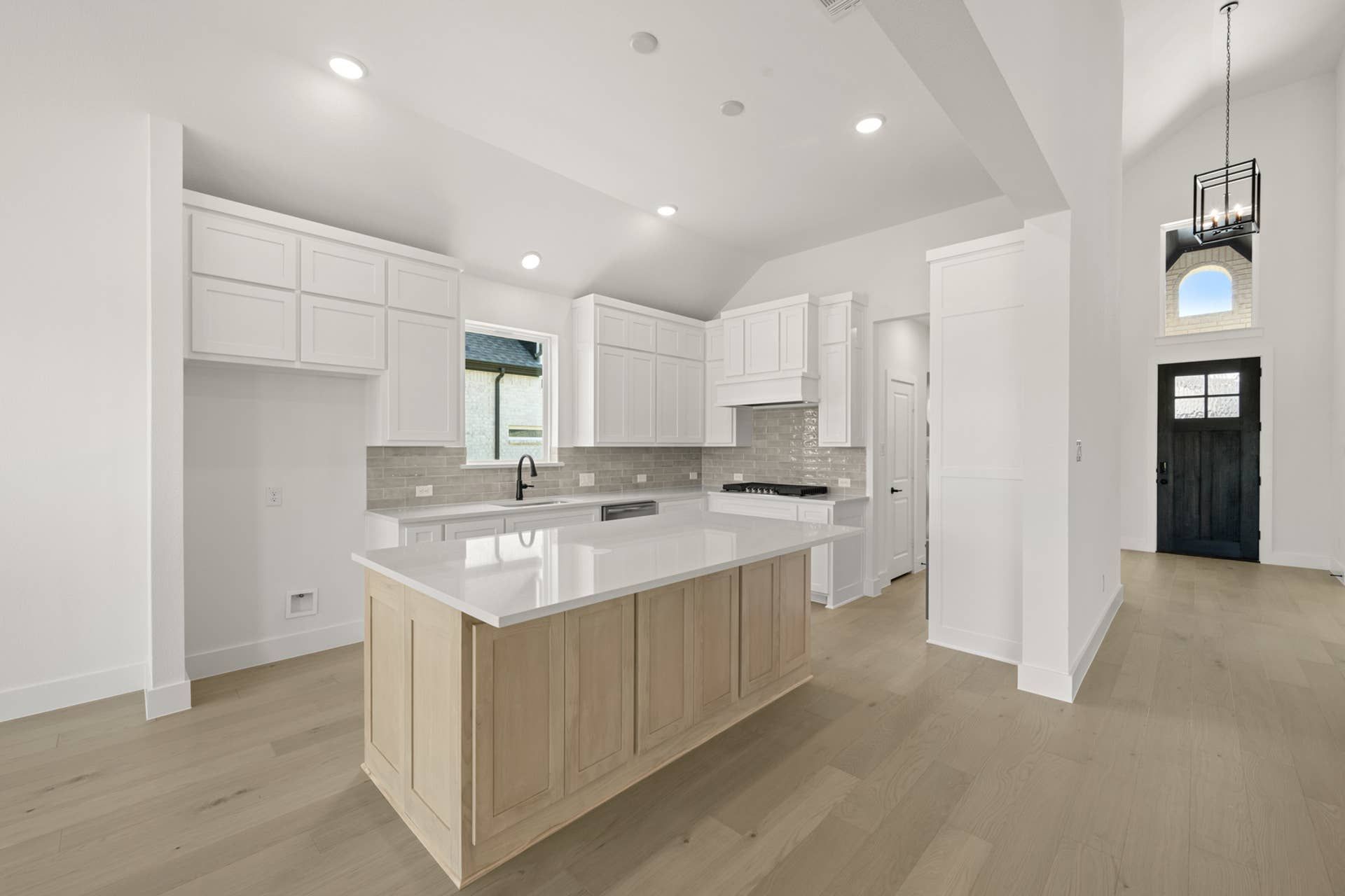 Modern kitchen with white cabinetry, large island, and light wood flooring.