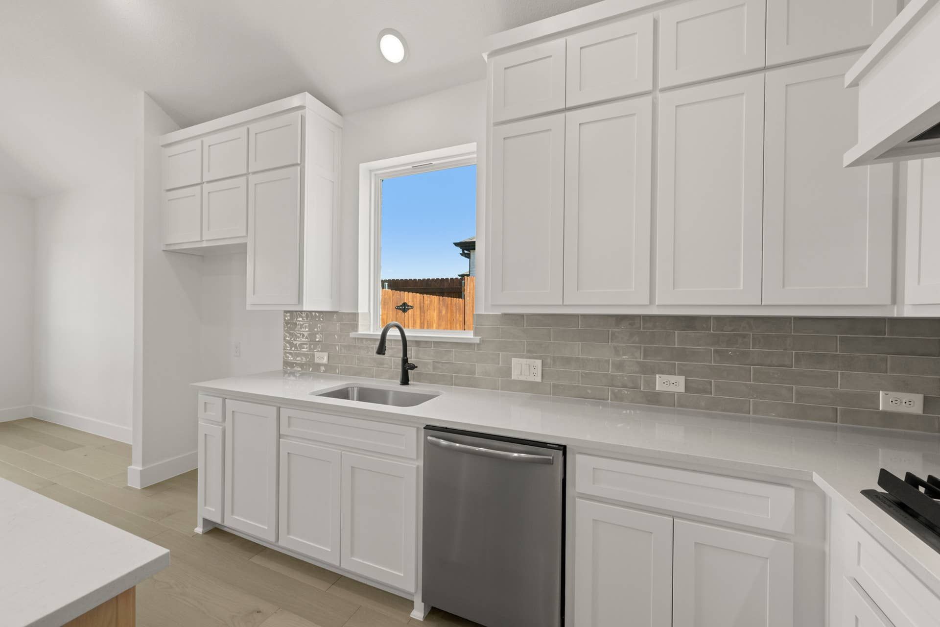 Modern kitchen with white cabinets and stainless steel appliances.