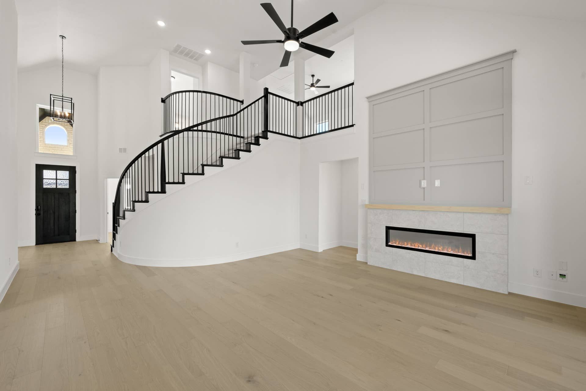 Spacious living room with curved staircase and modern fireplace.