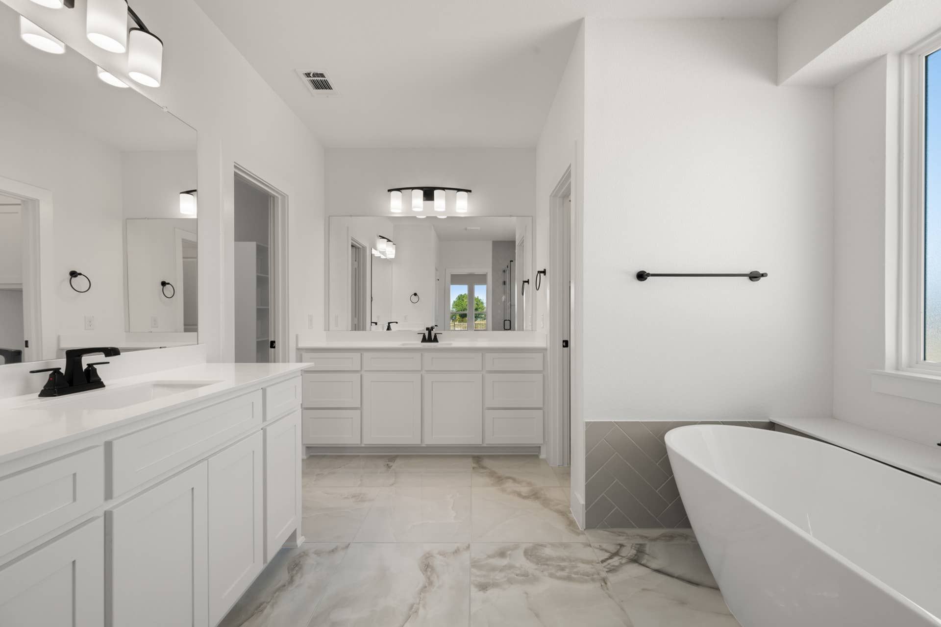 Spacious primary suite bathroom with dual vanities, soaking tub, and modern fixtures.