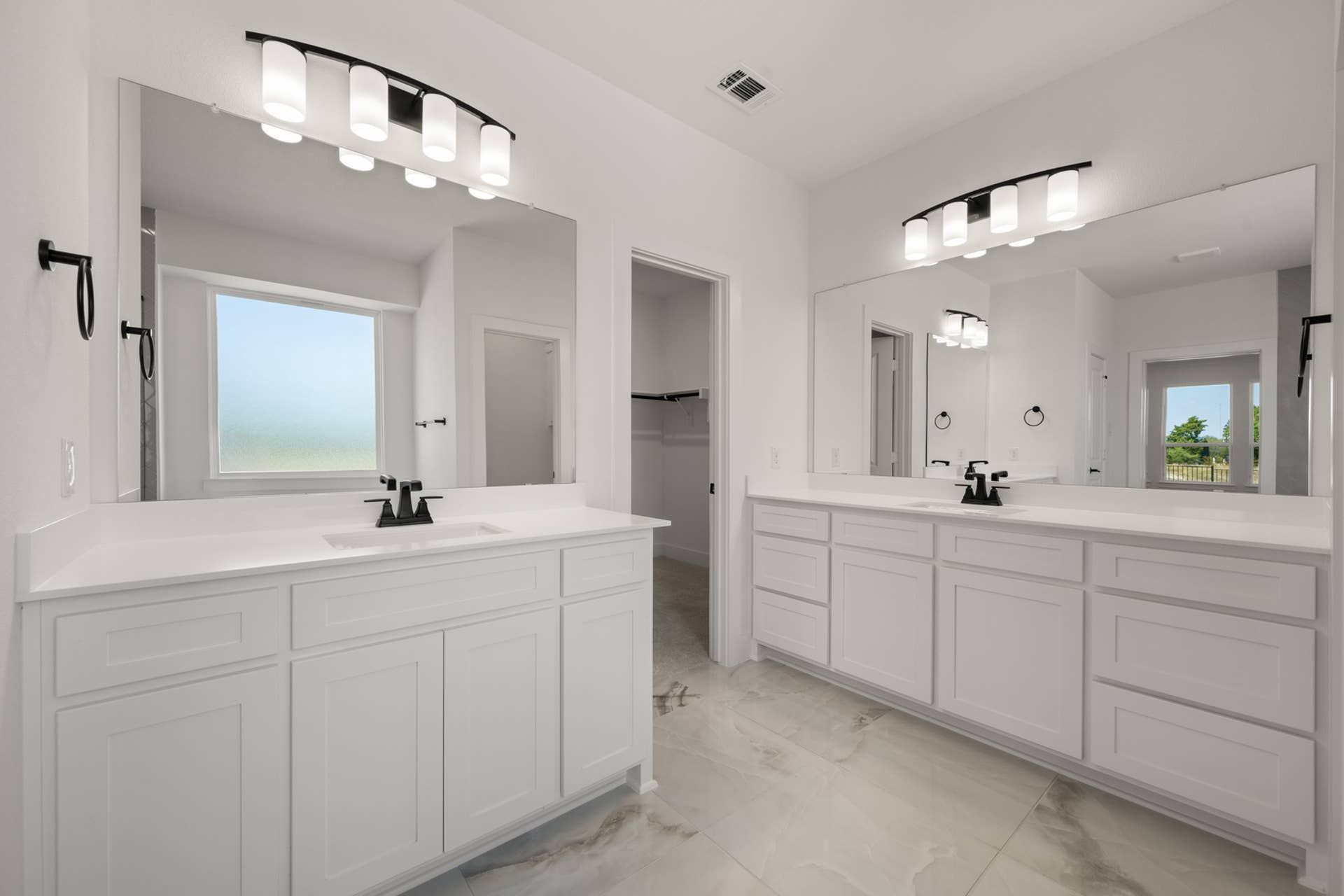 Luxurious bathroom with dual vanities, large mirrors, and modern light fixtures.