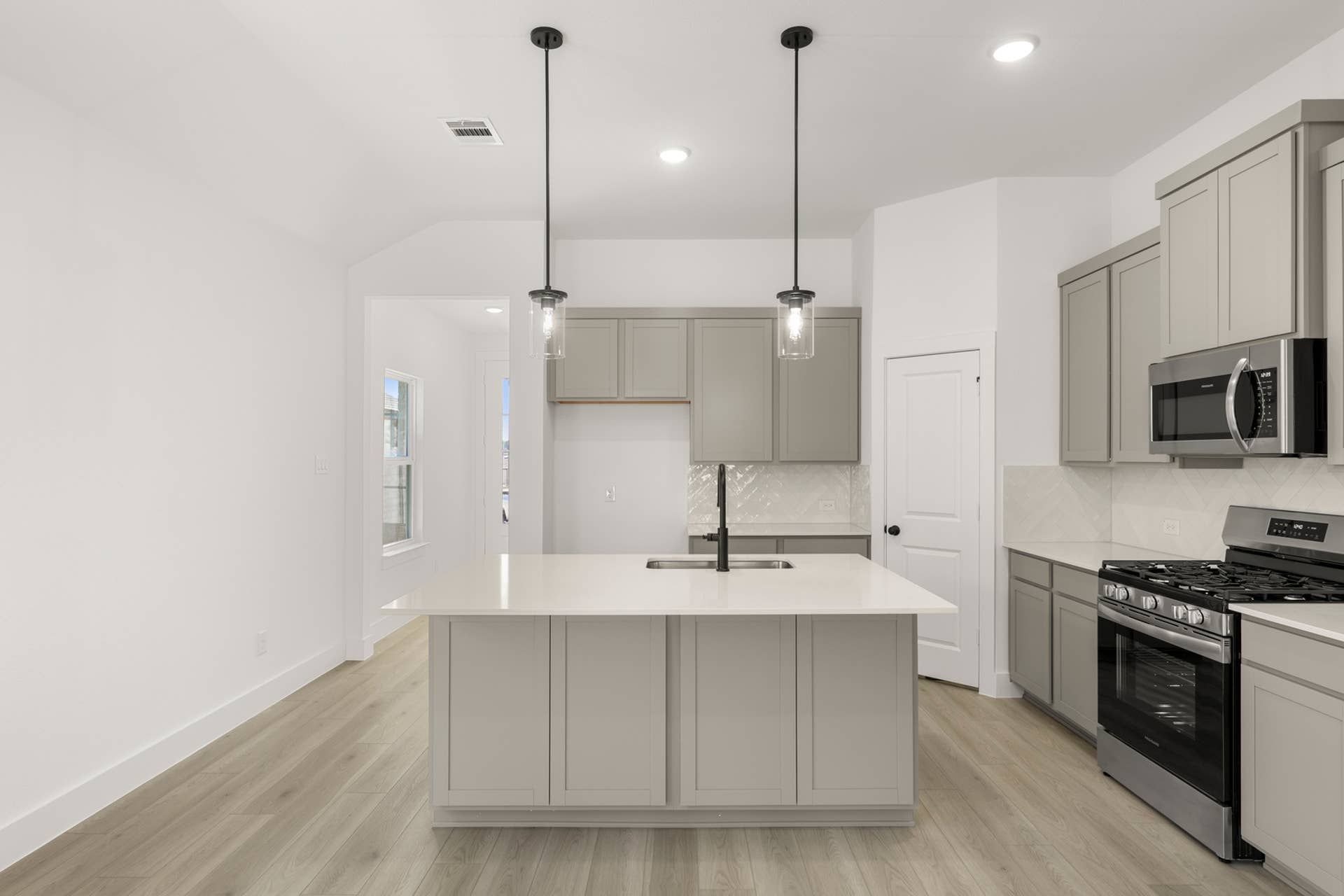 Modern kitchen with island, pendant lighting, and stainless steel appliances.