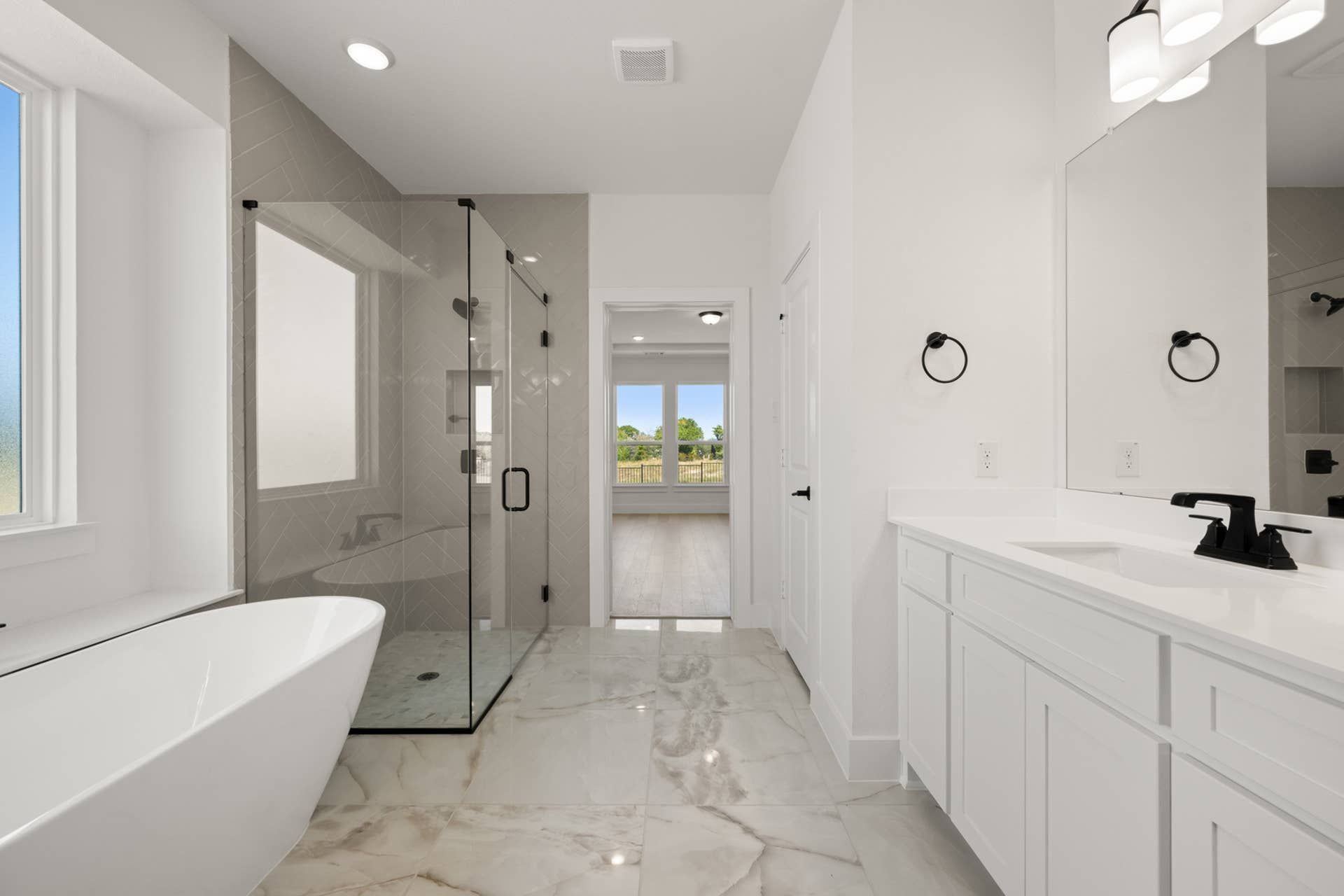 Luxurious primary suite bathroom with freestanding tub and glass-enclosed shower.