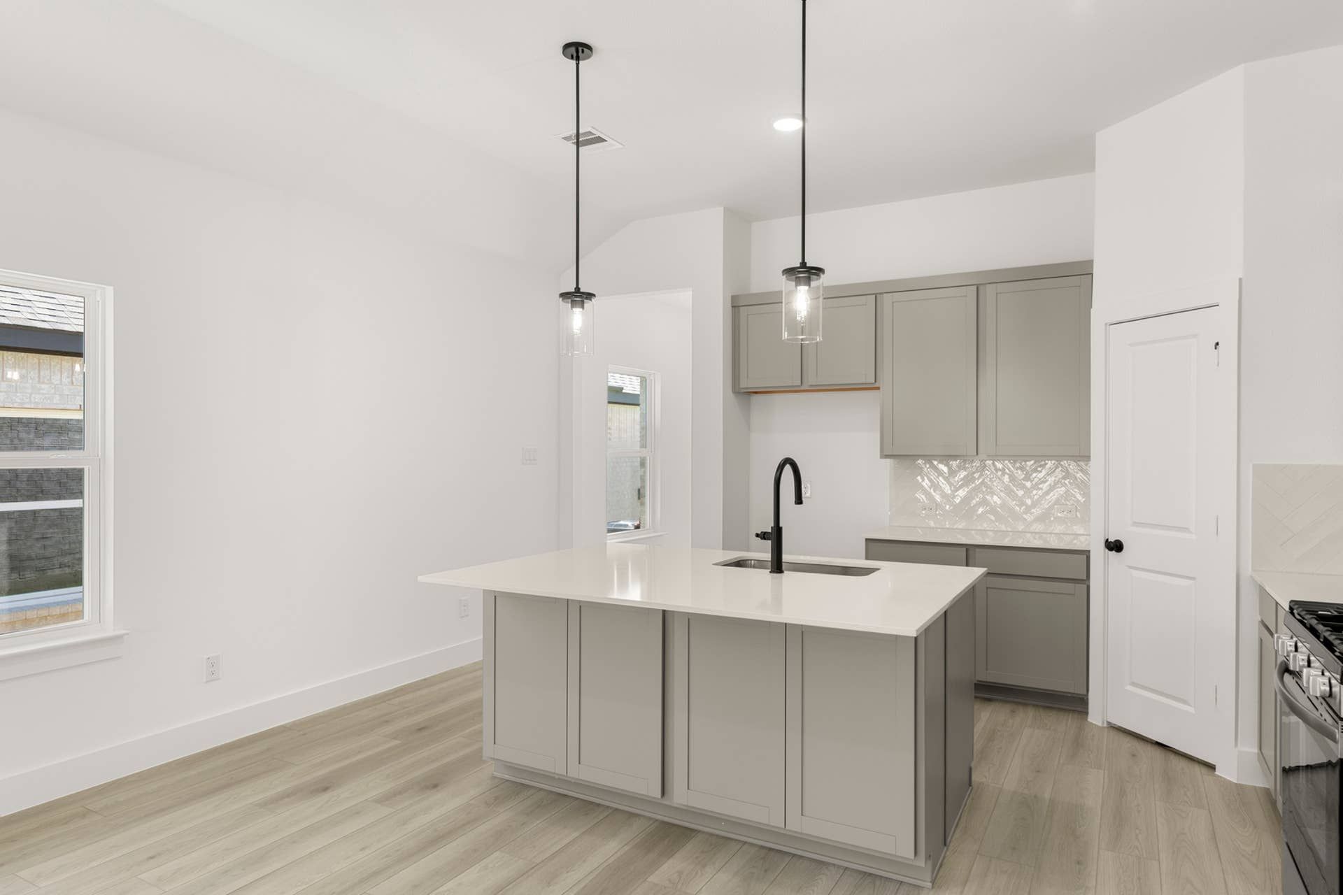 Modern kitchen with island, pendant lighting, and herringbone backsplash.