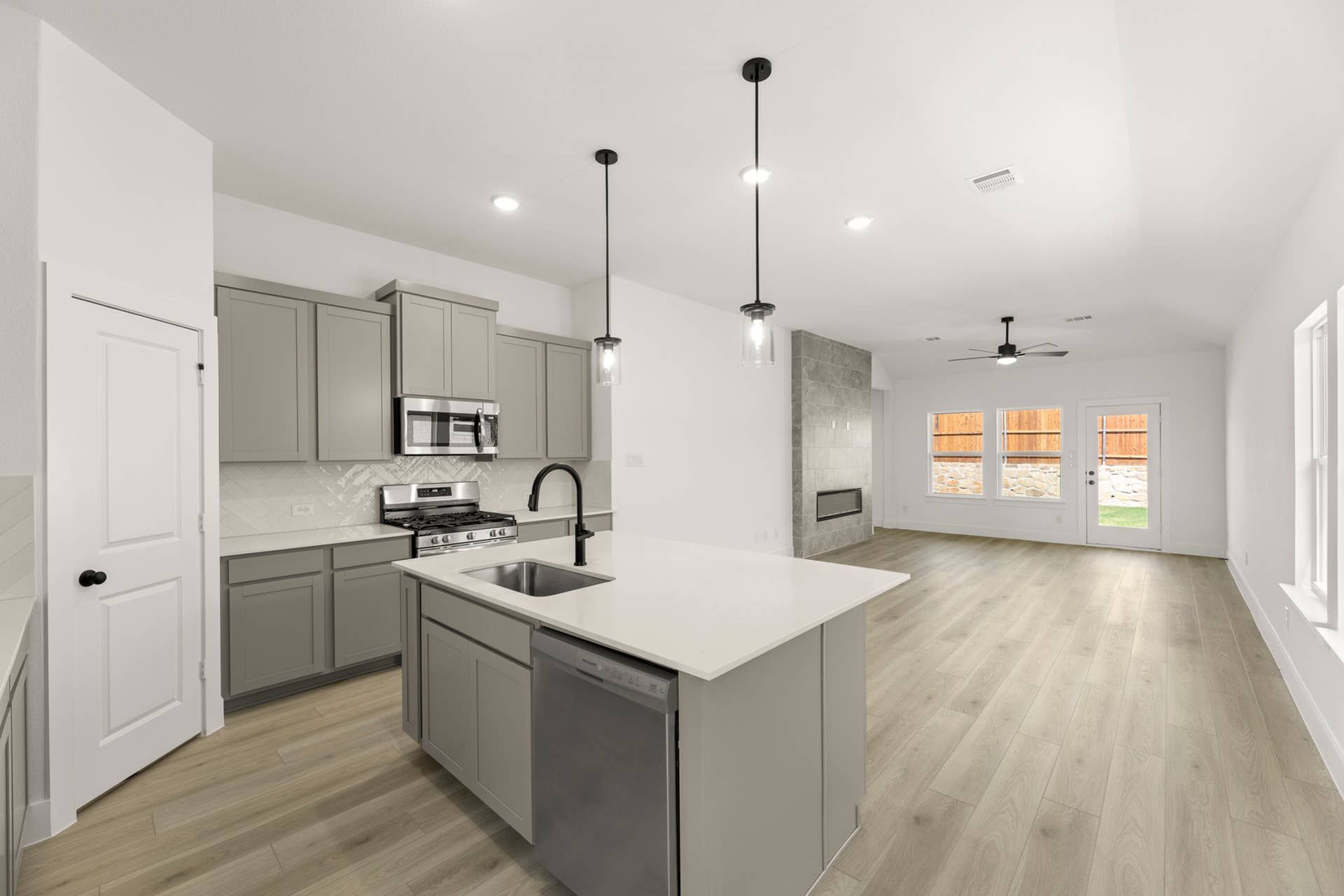 Modern kitchen with island, pendant lights, and open living area view.