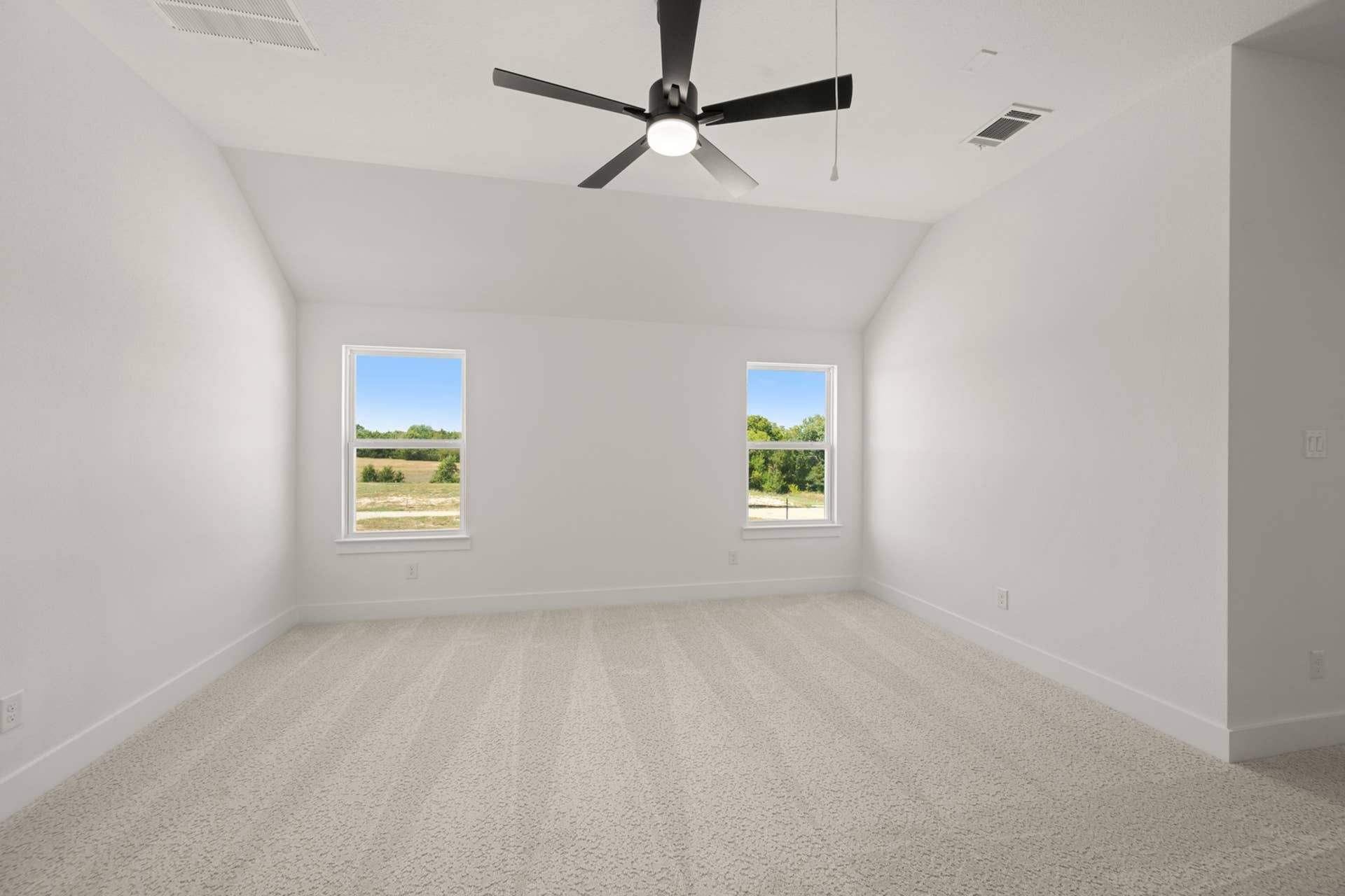 Spacious, bright game room with carpet and modern ceiling fan.