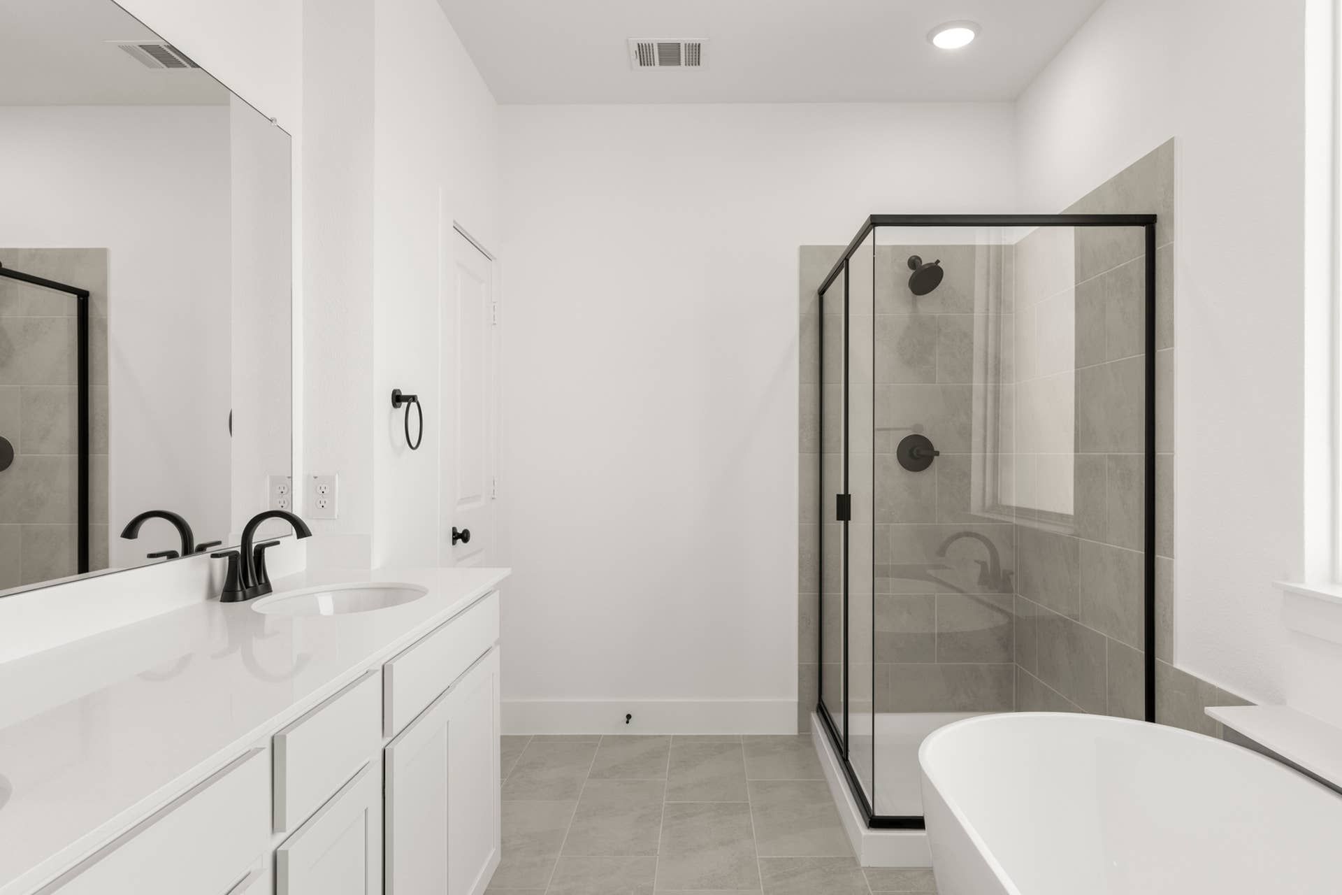 Modern bathroom with double vanity, glass shower, and freestanding bathtub.