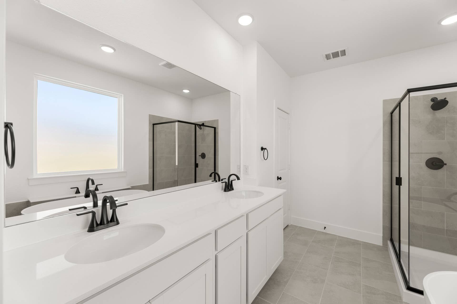 Modern bathroom with double vanity, large mirror, and glass-enclosed shower.