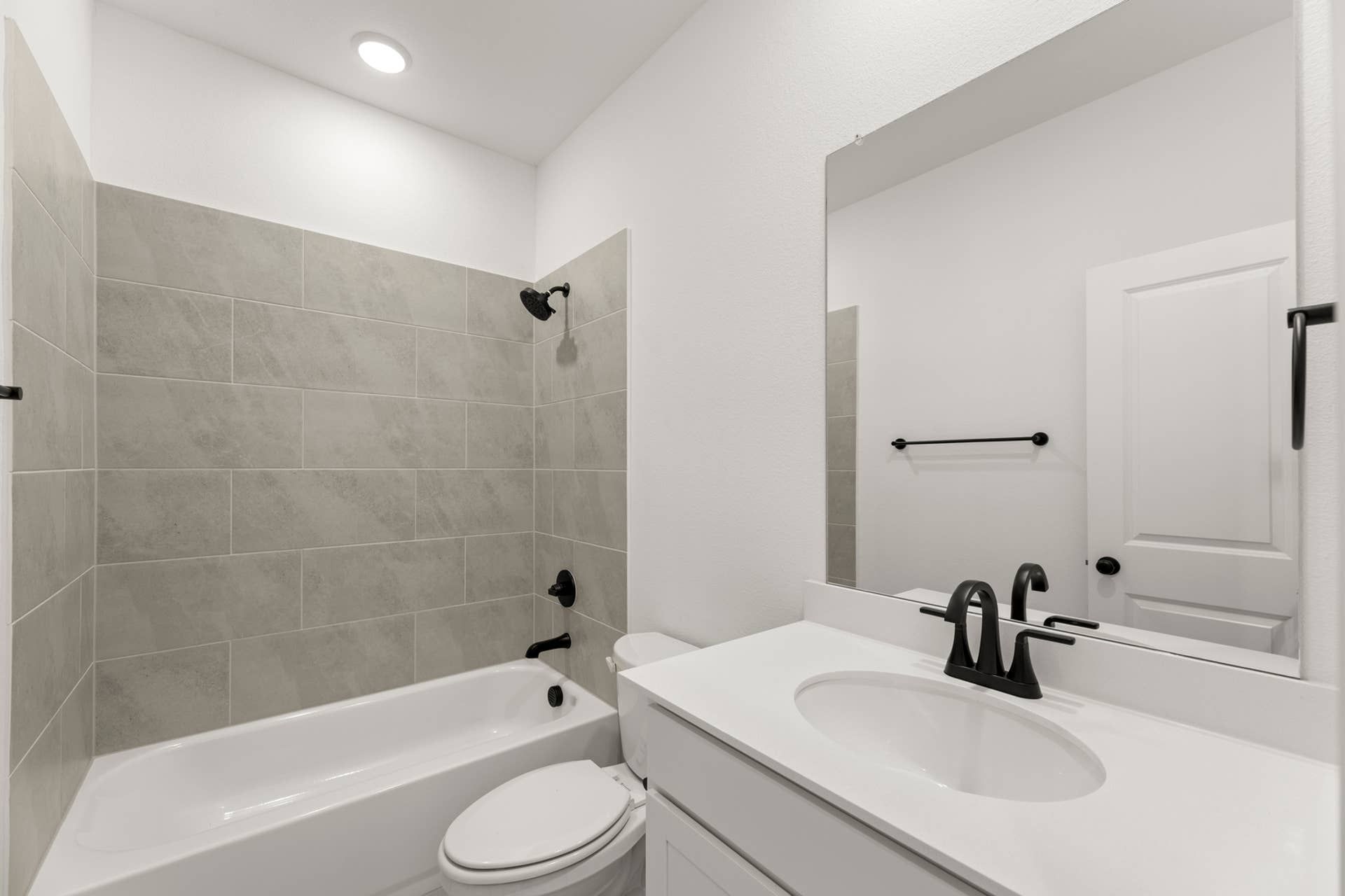 Modern bathroom with white vanity, large mirror, and tiled bathtub.