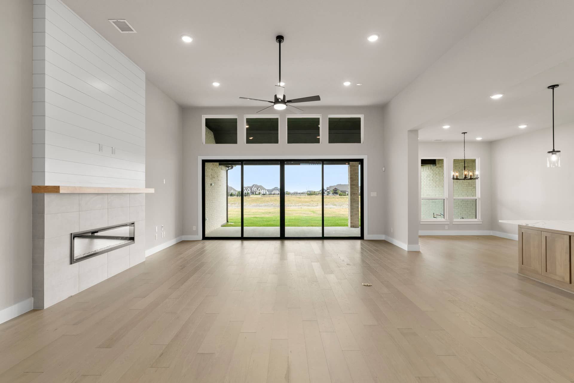 Spacious modern living area with fireplace and large glass doors to backyard view.